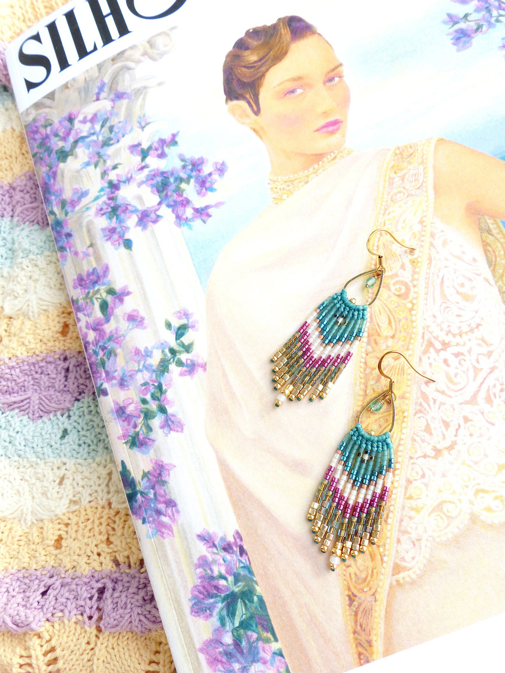 Peut inclure: Boucles d'oreilles en perles dorées en forme de larme. Les boucles d'oreilles sont faites de perles turquoise, blanches et roses. Les boucles d'oreilles sont suspendues à des crochets dorés.