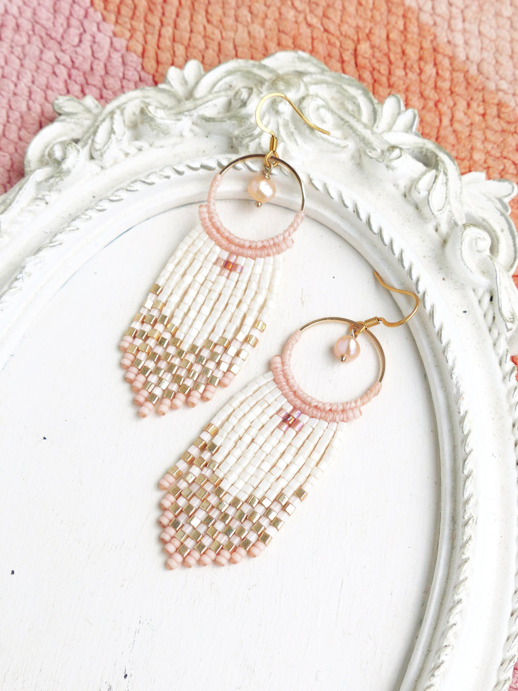 Peut inclure: Une paire de longues boucles d'oreilles en perles de couleur rose et blanche. Les boucles d'oreilles présentent une petite perle ronde rose au sommet de chaque boucle d'oreille et un anneau en or.