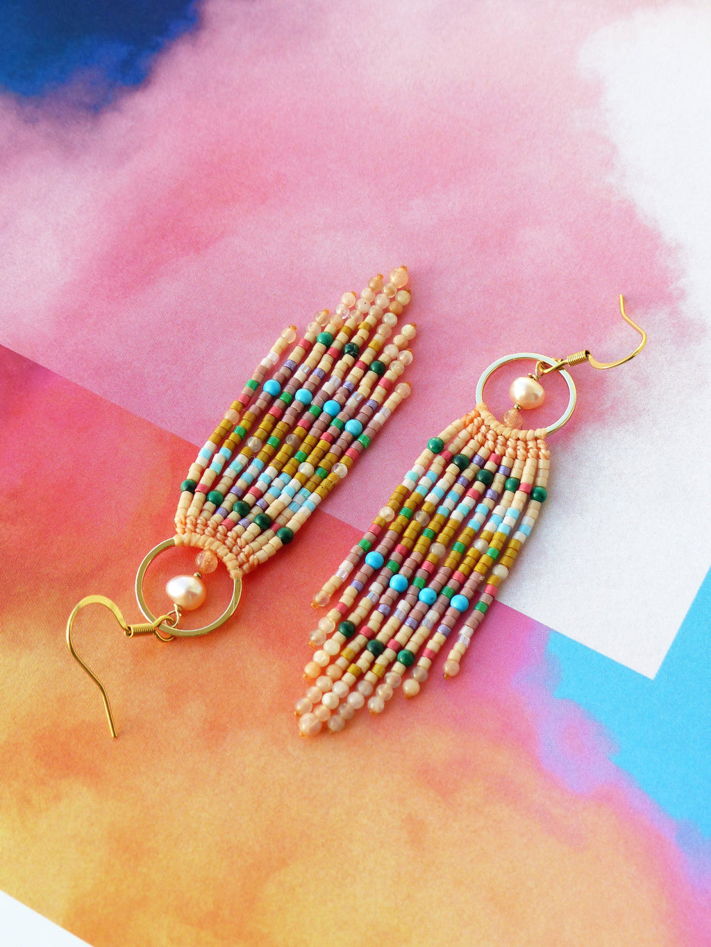 Peut inclure: Une paire de longues boucles d'oreilles en perles avec un anneau en or et un accent de perle. Les boucles d'oreilles sont faites avec une variété de perles colorées, y compris le rose, le jaune, le bleu, le vert et le marron.