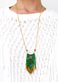 Peut inclure: Un collier en chaîne dorée avec un pendentif en perles vertes et dorées. Le pendentif a la forme d'une larme et est orné d'une frange de perles dorées.