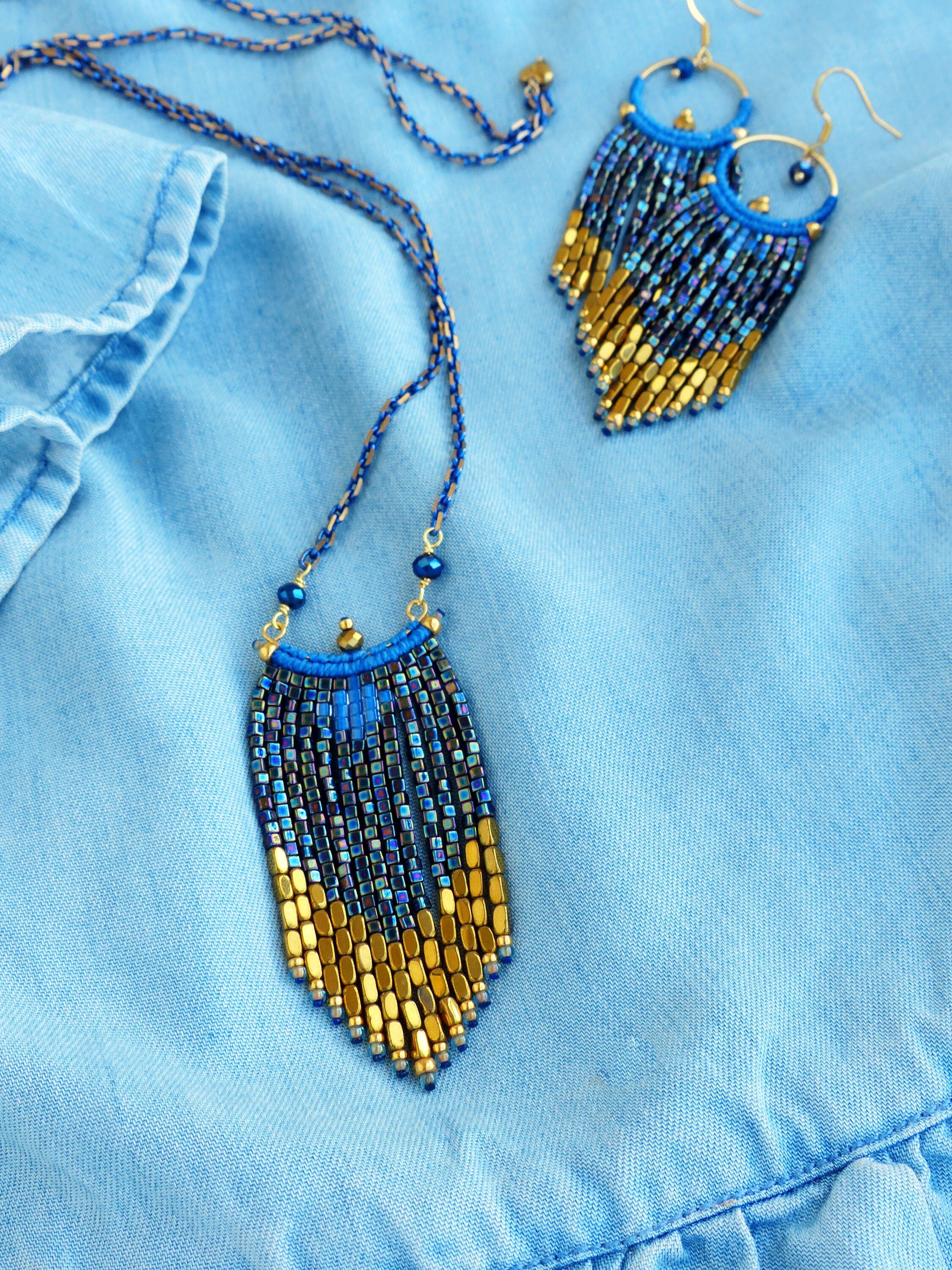 Peut inclure: Un collier et des boucles d'oreilles assortis en perles bleues et dorées. Le collier et les boucles d'oreilles ont un design en frange avec des perles dorées en bas.