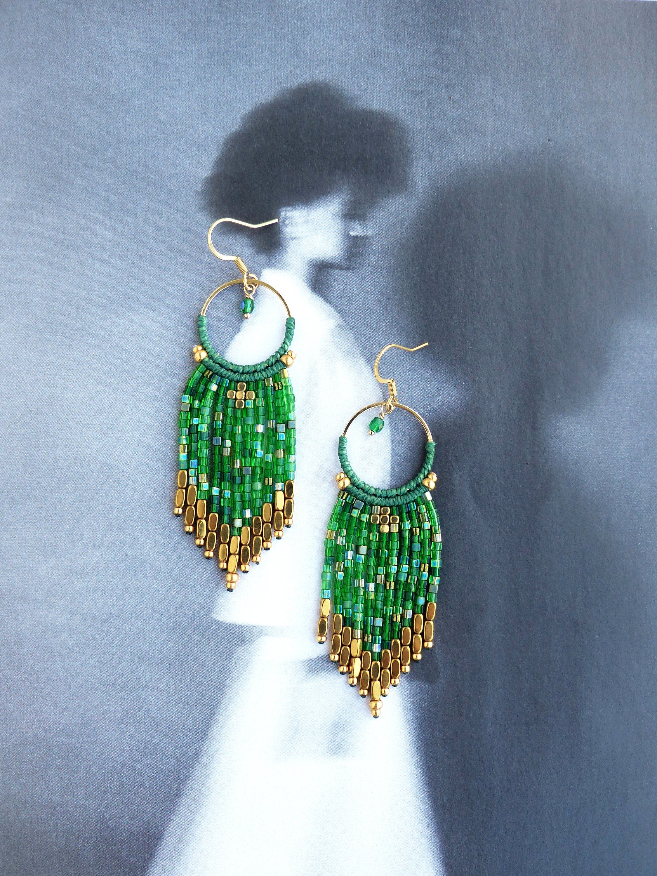 Peut inclure: Boucles d'oreilles en perles vertes et dorées avec un design en frange. Les boucles d'oreilles sont faites de petites perles rondes et de métal doré.