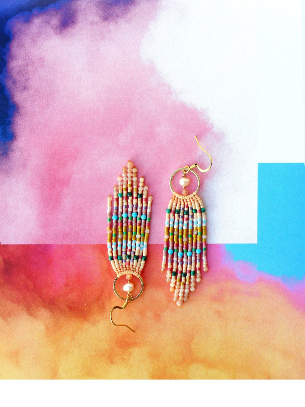 Peut inclure: Une paire de longues boucles d'oreilles en perles avec un anneau en or et un accent de perle. Les boucles d'oreilles sont faites avec une variété de perles colorées, y compris le rose, l'orange, le jaune, le vert et le bleu.