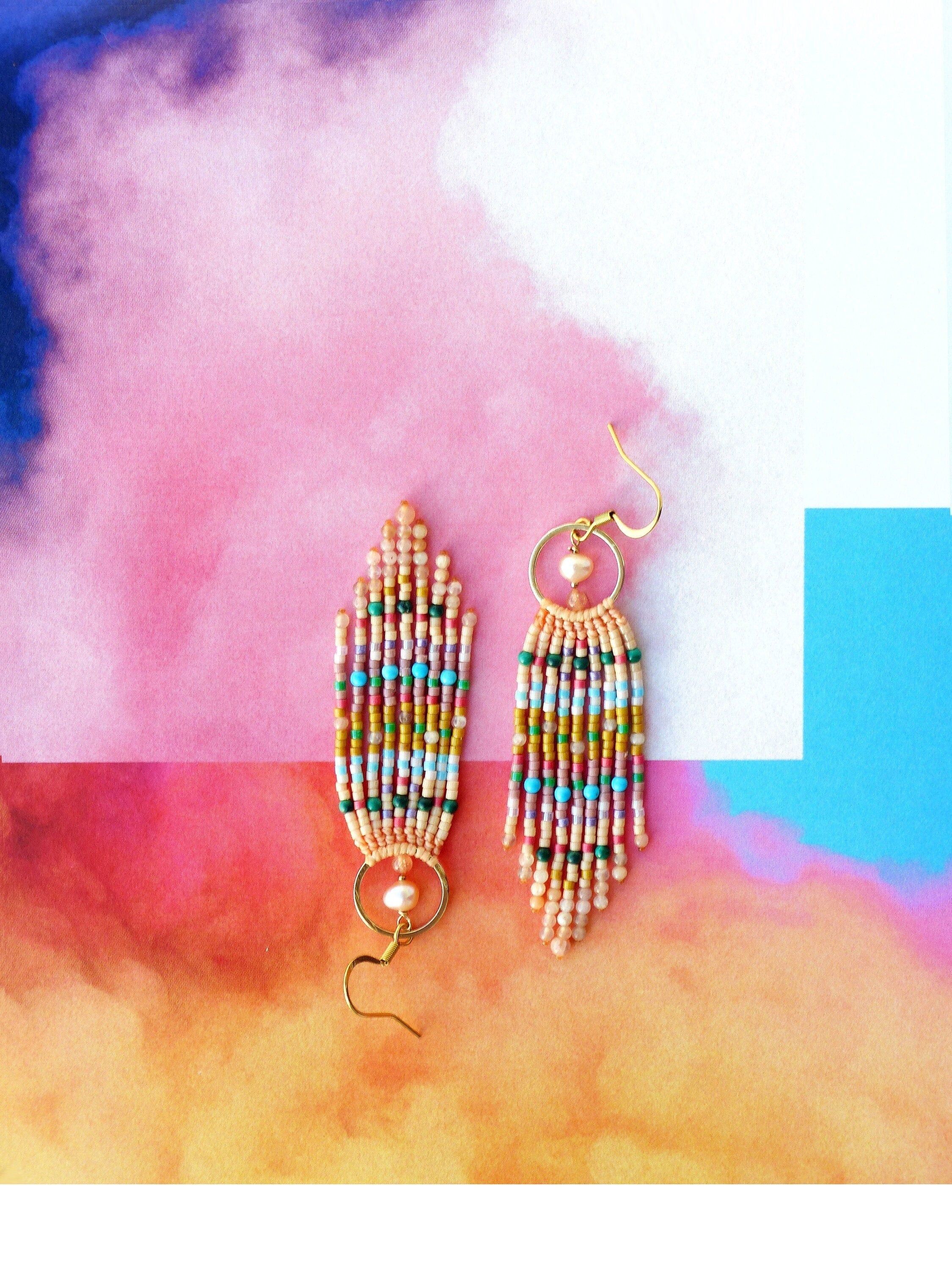 Peut inclure: Une paire de longues boucles d'oreilles en perles avec un anneau en or et un accent de perle. Les boucles d'oreilles sont faites avec une variété de perles colorées, y compris le rose, l'orange, le jaune, le vert et le bleu.