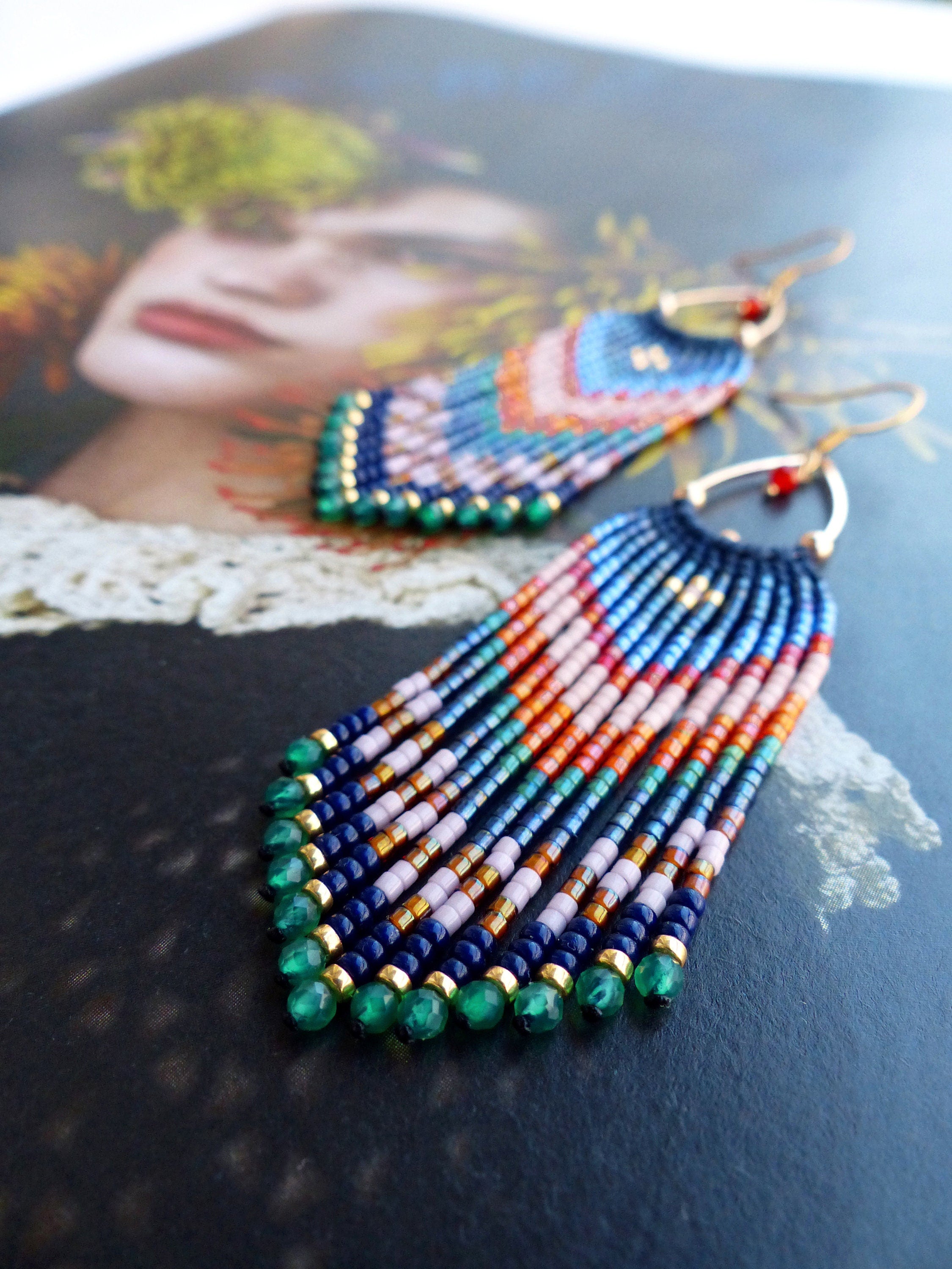 Peut inclure: Boucles d'oreilles faites à la main, composées de perles colorées. Les boucles d'oreilles présentent un mélange de perles bleues, roses, oranges et vertes, avec des accents dorés et des gouttes de pierres précieuses vertes. Design unique et à franges.
