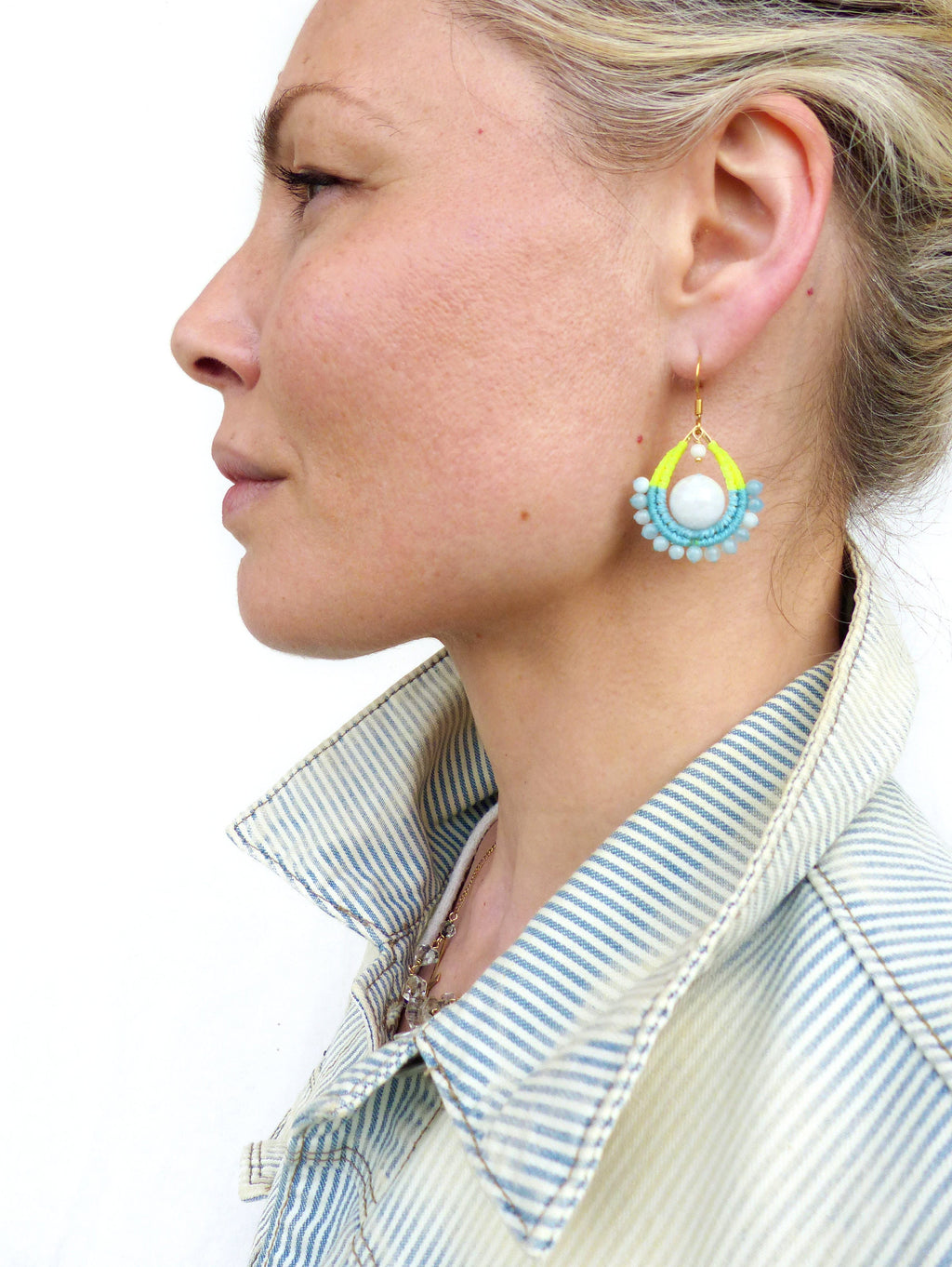 Peut inclure: Une paire de boucles d'oreilles en forme de goutte d'eau avec une perle blanche au centre. Les boucles d'oreilles sont faites de perles turquoise et jaunes et ont un crochet en or.