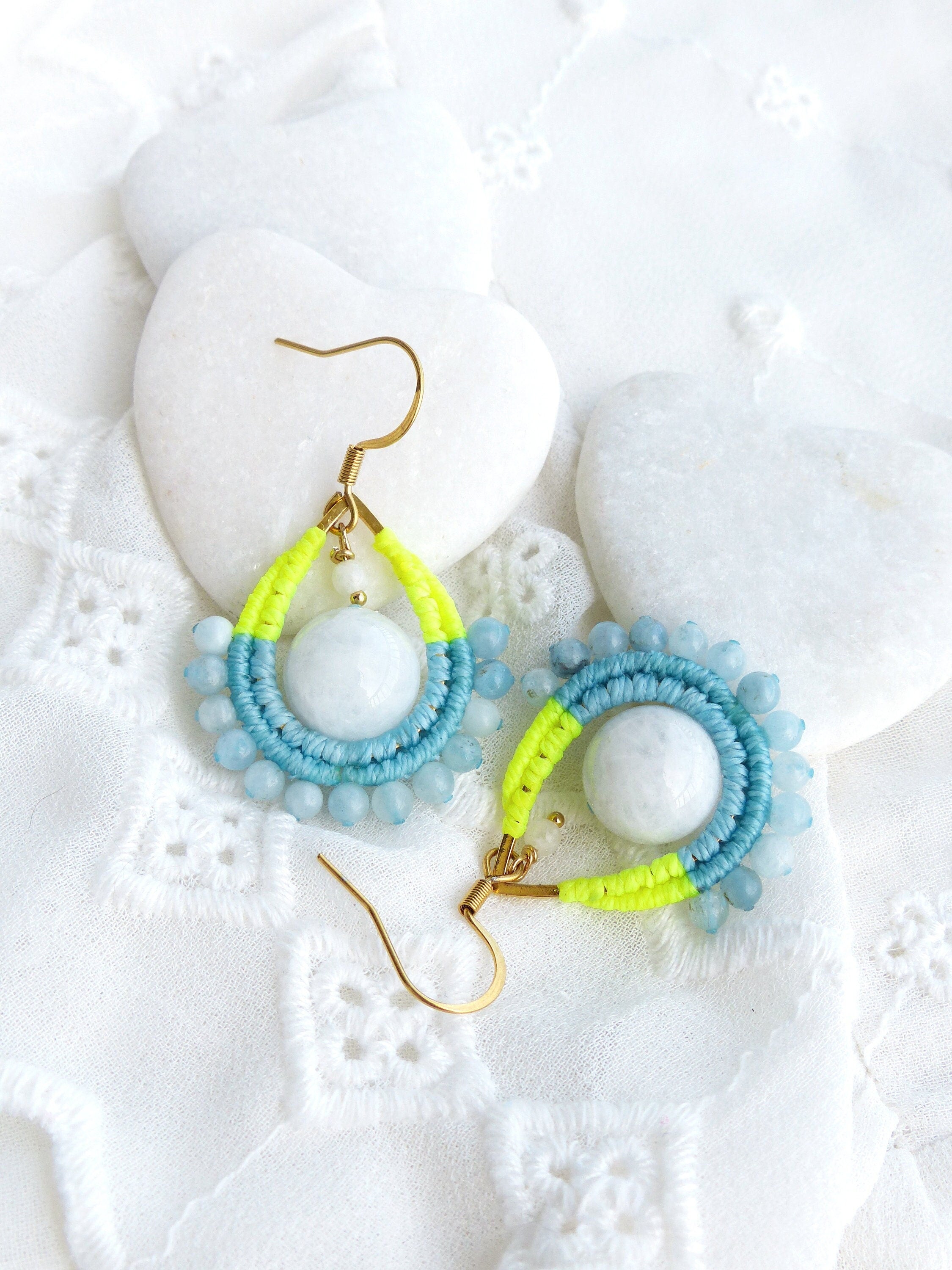 Peut inclure: Une paire de boucles d'oreilles pendantes avec un design de perles bleu clair et jaune fluo. Chaque boucle d'oreille présente une pierre ronde blanche au centre.