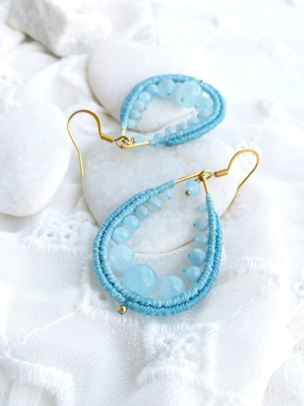 Peut inclure: Une paire de boucles d'oreilles en forme de larme bleu clair avec des anneaux dorés. Les boucles d'oreilles sont faites de plusieurs brins de perles bleues et de plus grosses perles de pierres précieuses bleu clair.
