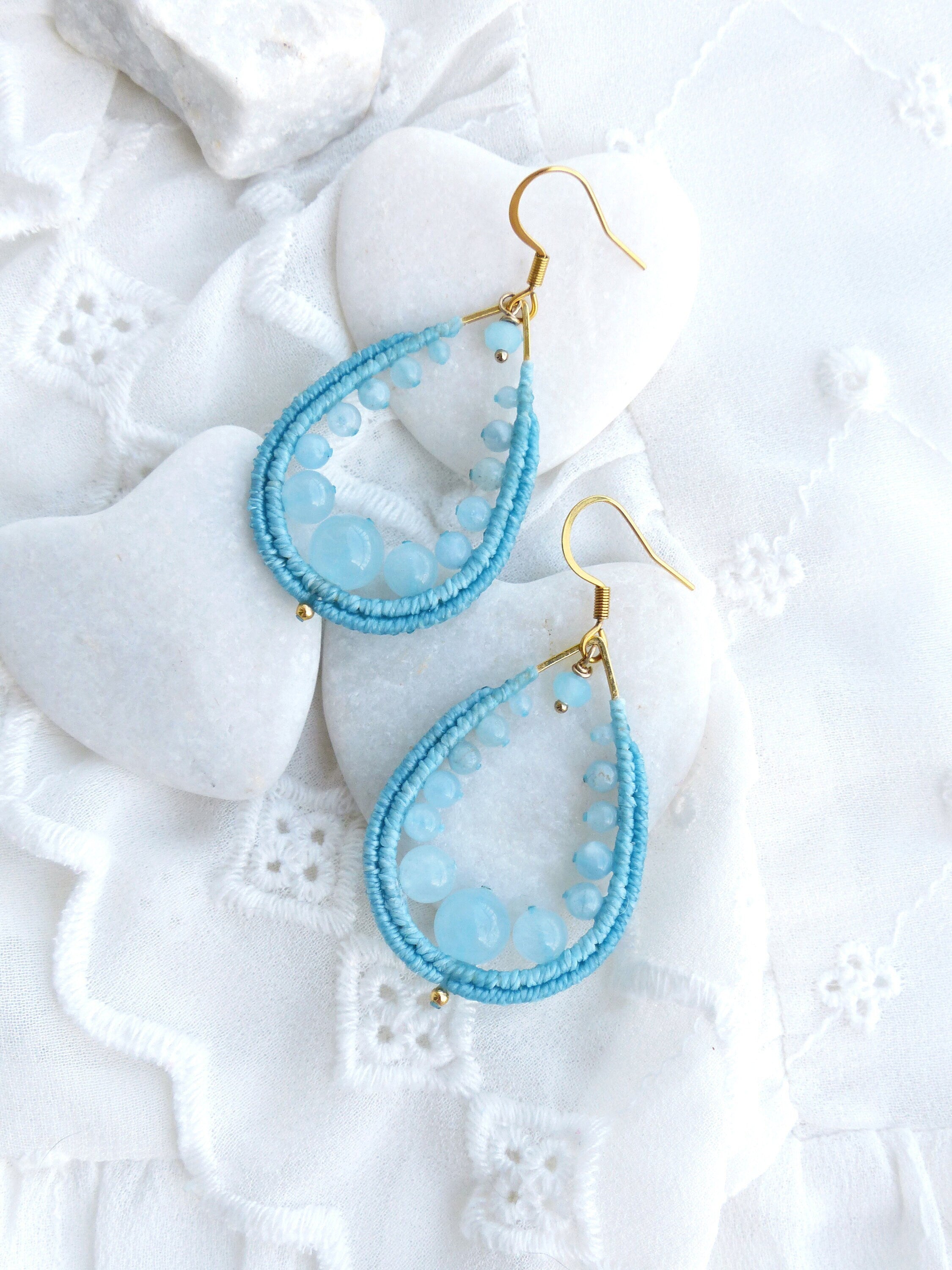Peut inclure: Une paire de boucles d'oreilles en forme de goutte d'eau avec un fil d'or enroulé de perles bleu clair et des accents de pierres précieuses bleu clair.