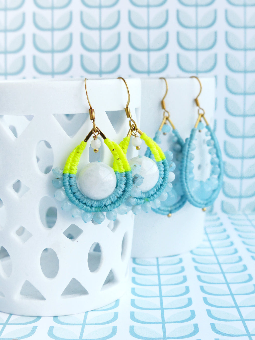 Peut inclure: Une paire de boucles d'oreilles pendantes en forme de larme. Les boucles d'oreilles sont faites de perles bleues et blanches et de ficelle jaune. Les boucles d'oreilles sont suspendues à des crochets dorés.