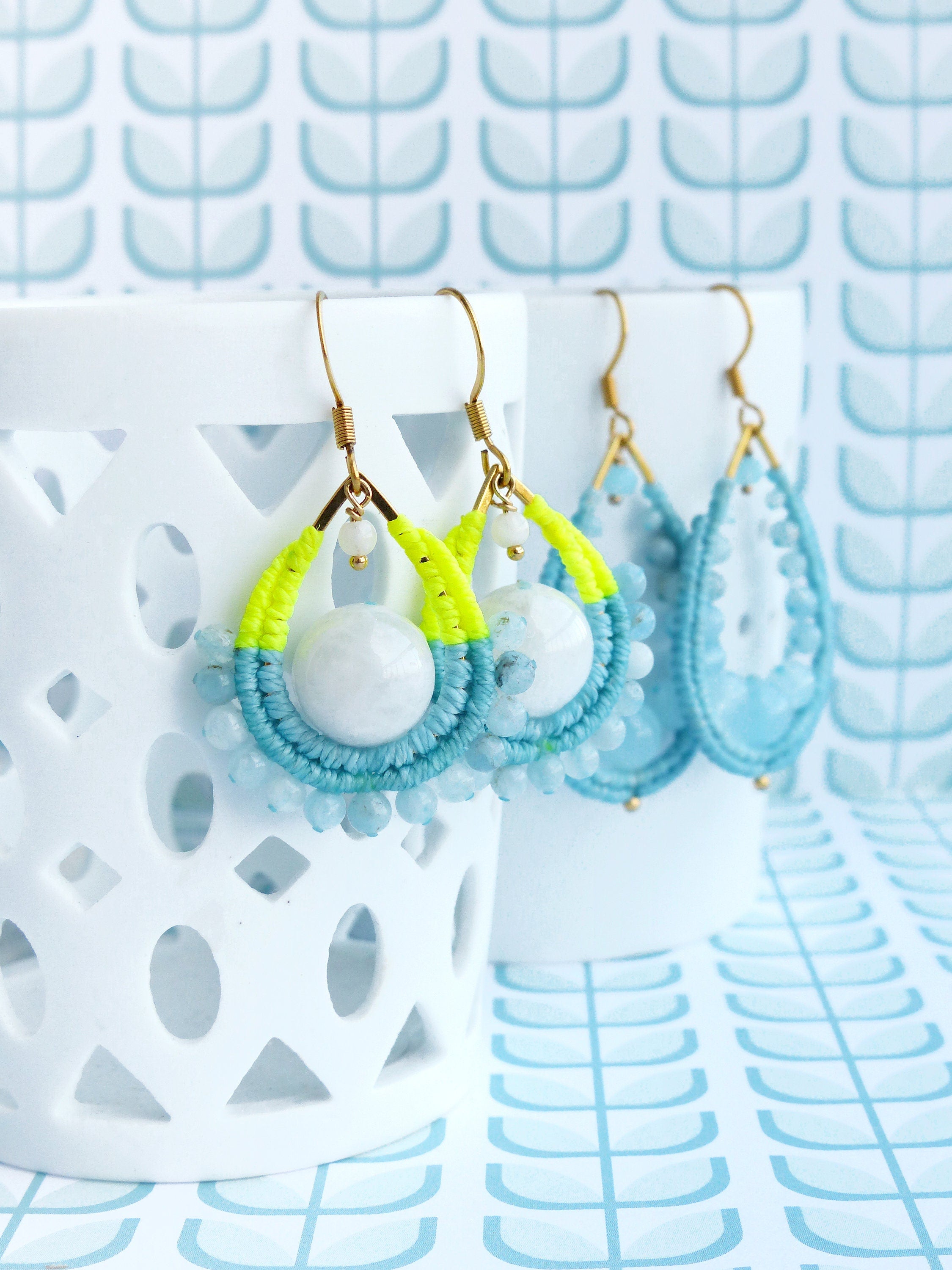 Peut inclure: Une paire de boucles d'oreilles pendantes en forme de larme. Les boucles d'oreilles sont faites de perles bleues et blanches et de ficelle jaune. Les boucles d'oreilles sont suspendues à des crochets dorés.