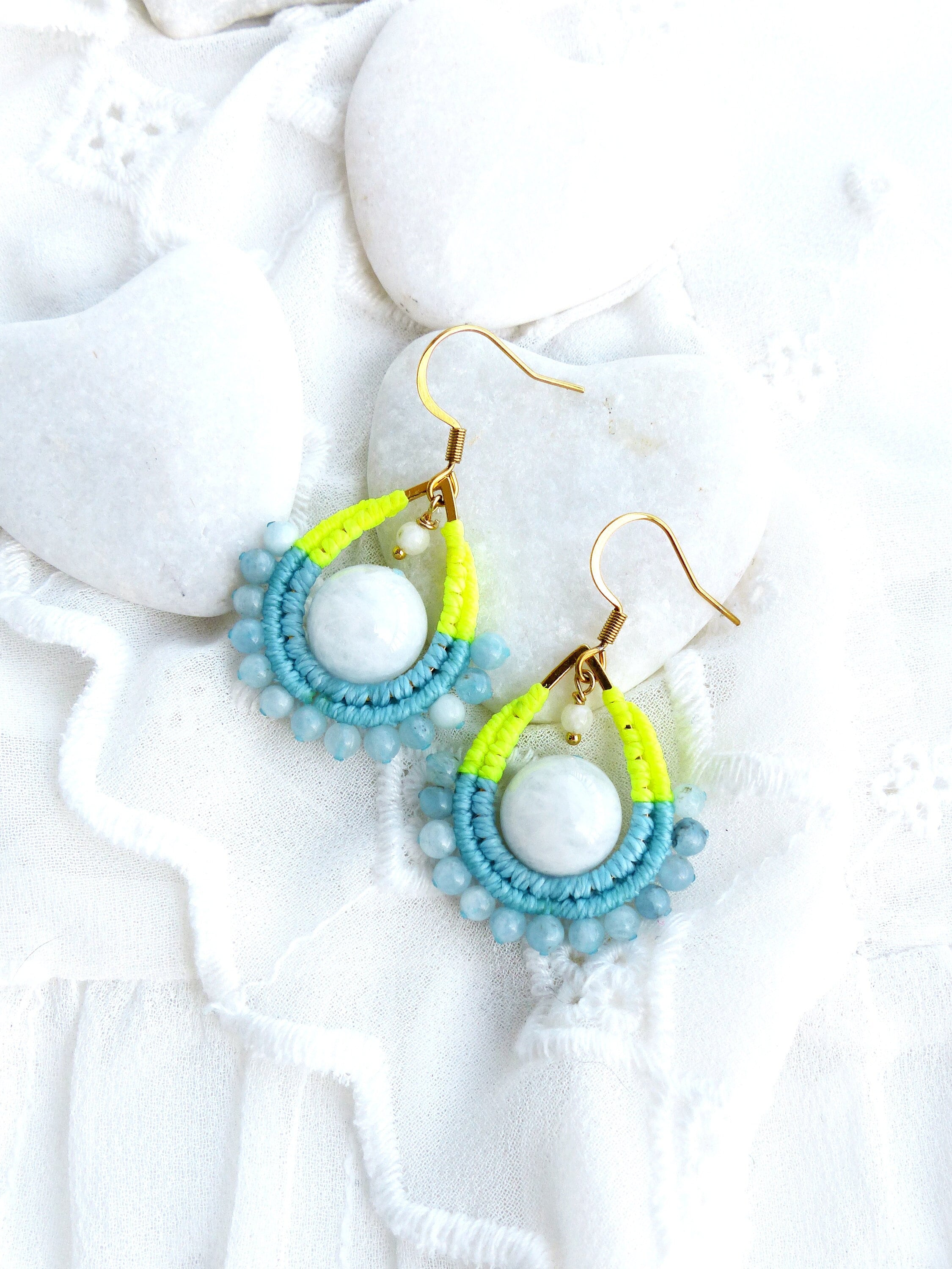 Peut inclure: Une paire de boucles d'oreilles pendantes avec une pierre blanche entourée de perles bleues et jaunes.
