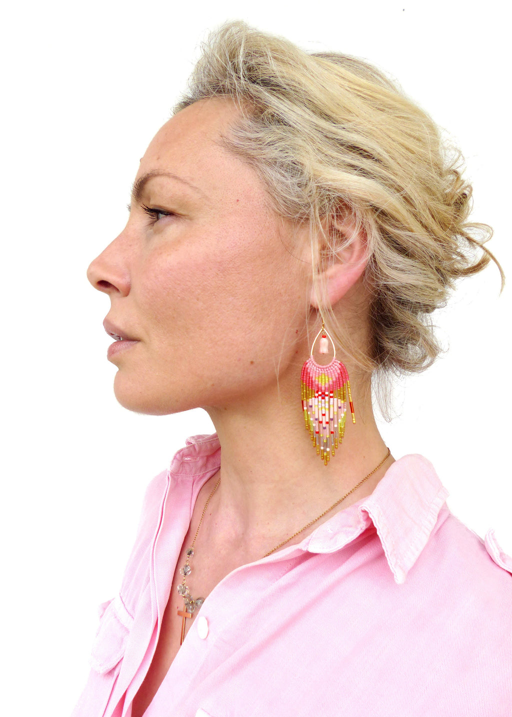 Peut inclure: Une femme portant une chemise rose avec un collier en chaîne dorée et des boucles d'oreilles en perles. Les boucles d'oreilles sont roses, blanches et dorées et ont une forme de larme.