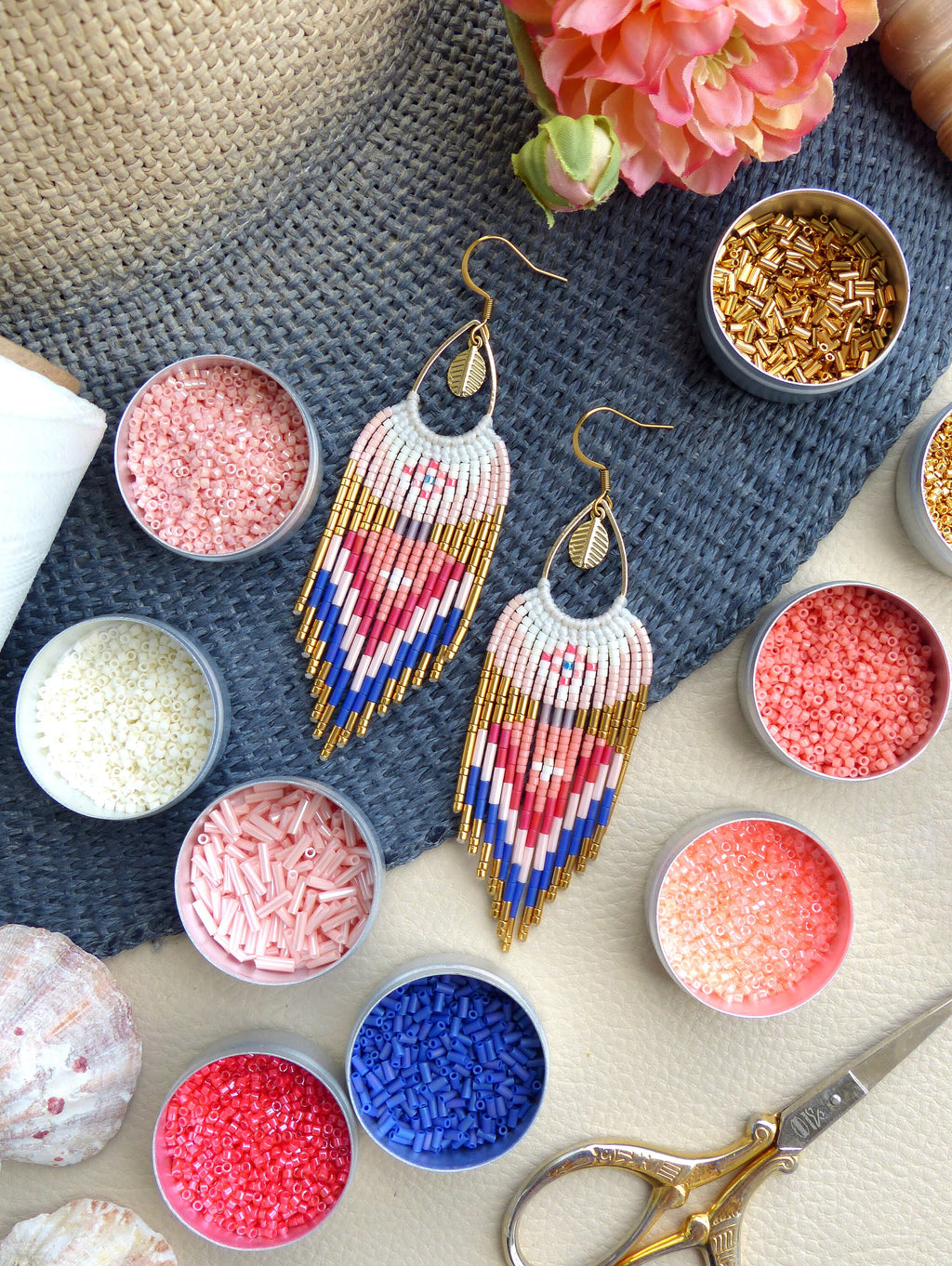 Peut inclure: Une paire de boucles d'oreilles en perles faites à la main avec un motif géométrique dans des tons de rose, bleu et or. Les boucles d'oreilles sont faites avec de petites perles de rocaille et présentent un charme en feuille d'or en haut.