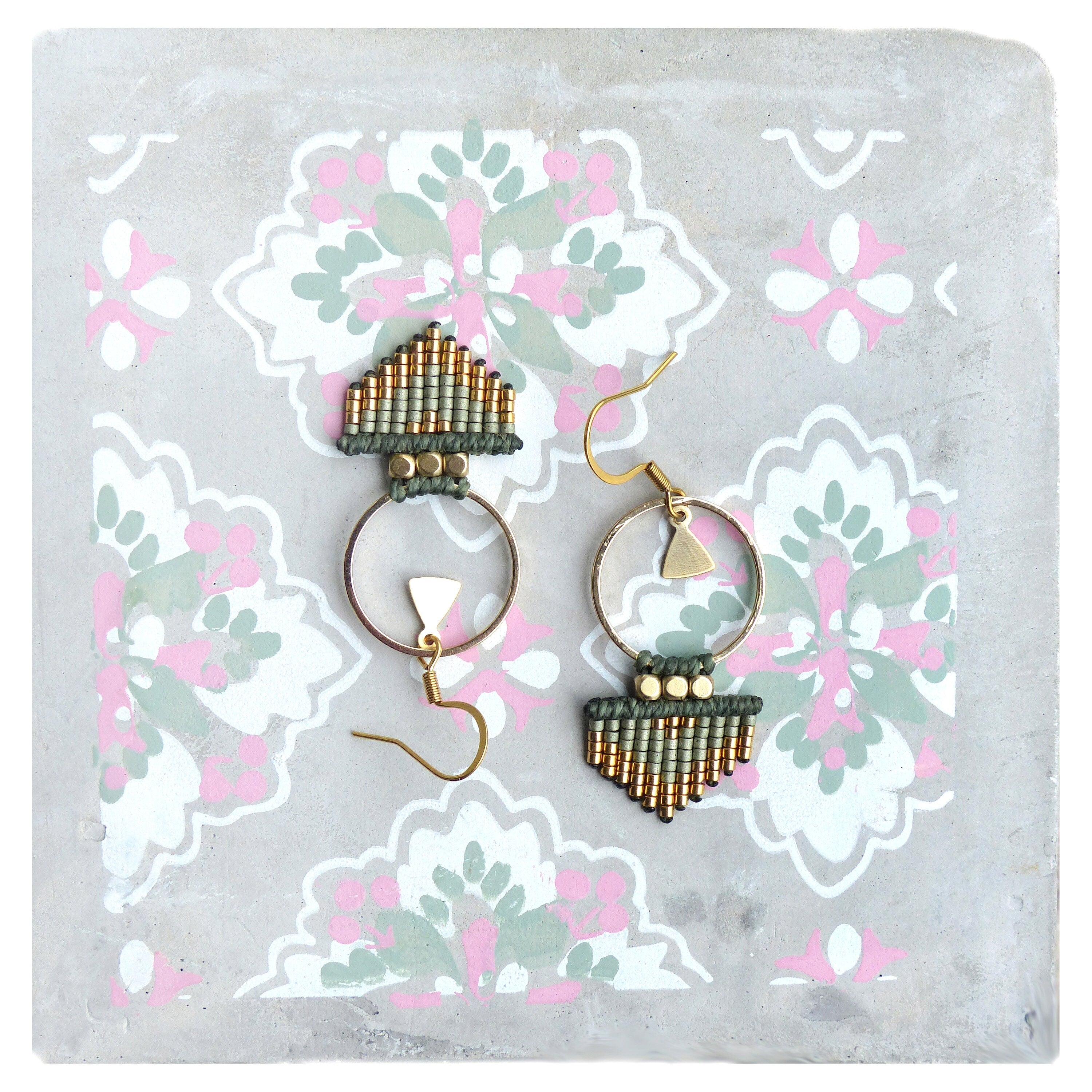 Peut inclure: Une paire de boucles d'oreilles en perles dorées et vertes avec un motif géométrique. Les boucles d'oreilles présentent un anneau et une forme triangulaire pendante.