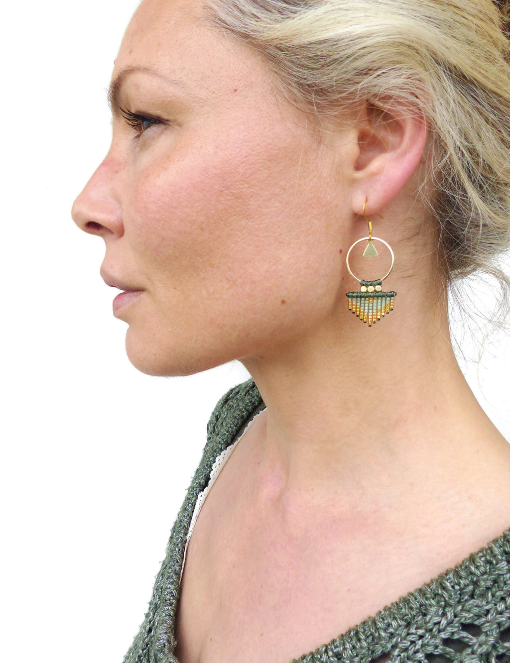 Peut inclure: Boucles d'oreilles créoles dorées avec un pendentif triangulaire en perles vertes et dorées.