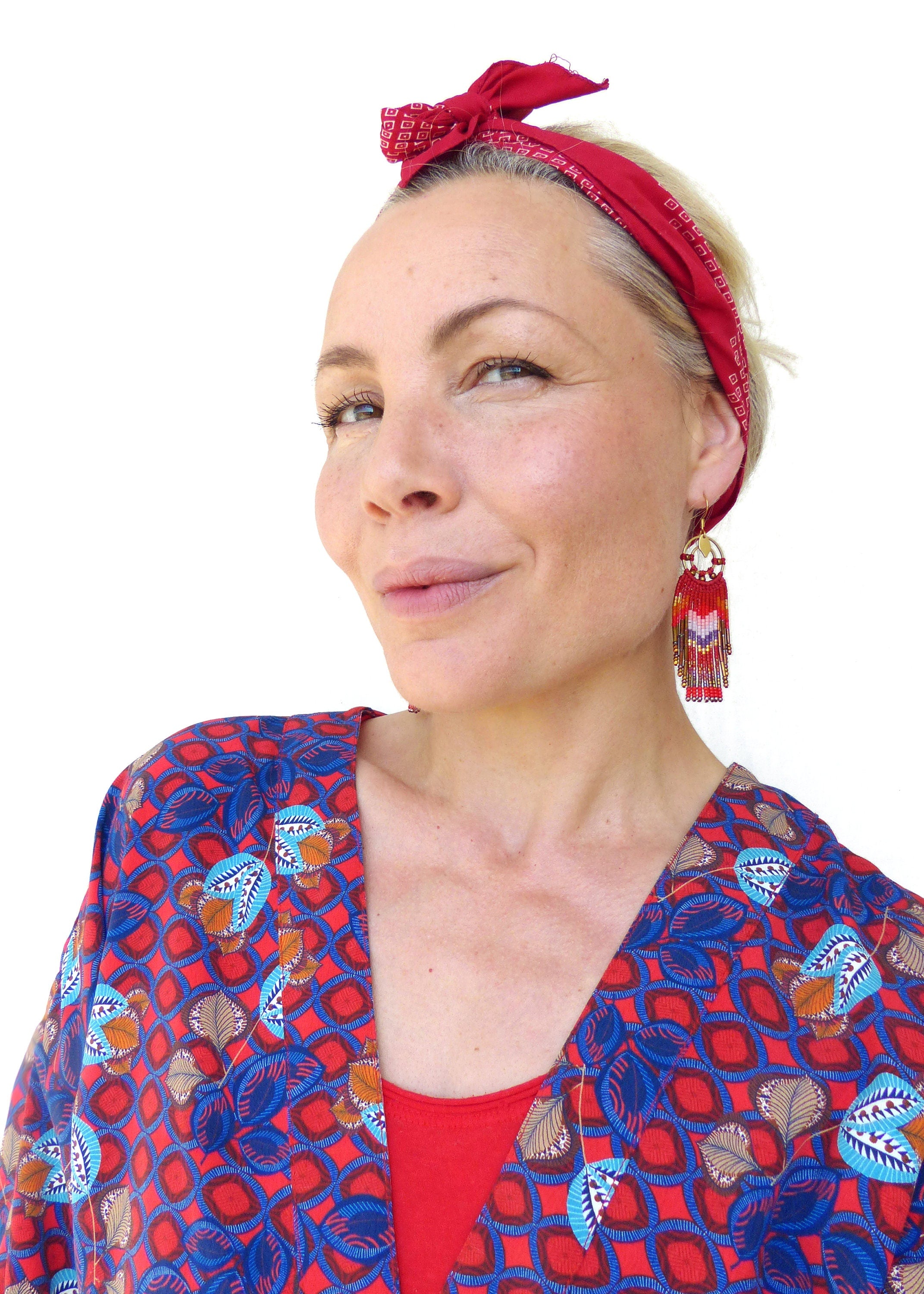 Peut inclure: Une femme portant un kimono à motifs rouge et bleu avec un bandana rouge noué autour de la tête. Elle porte des boucles d'oreilles rouges avec des accents dorés.