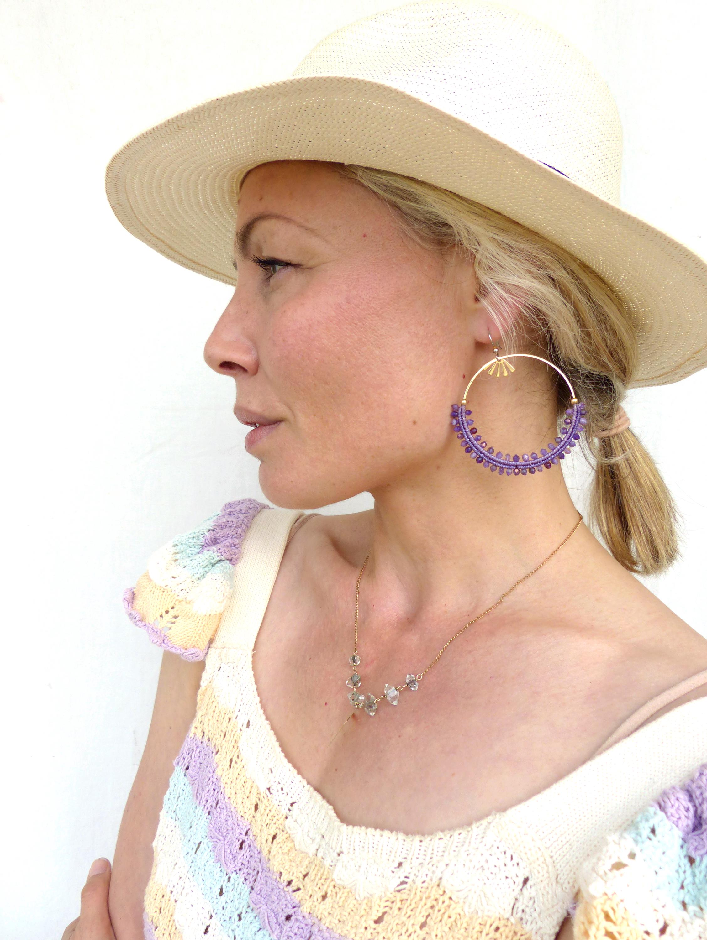 Peut inclure: Un chapeau de soleil couleur paille à larges bords. Boucles d'oreilles créoles dorées avec des perles violettes et un collier pendentif doré avec des pierres transparentes. Le haut est à motifs arc-en-ciel pastel.