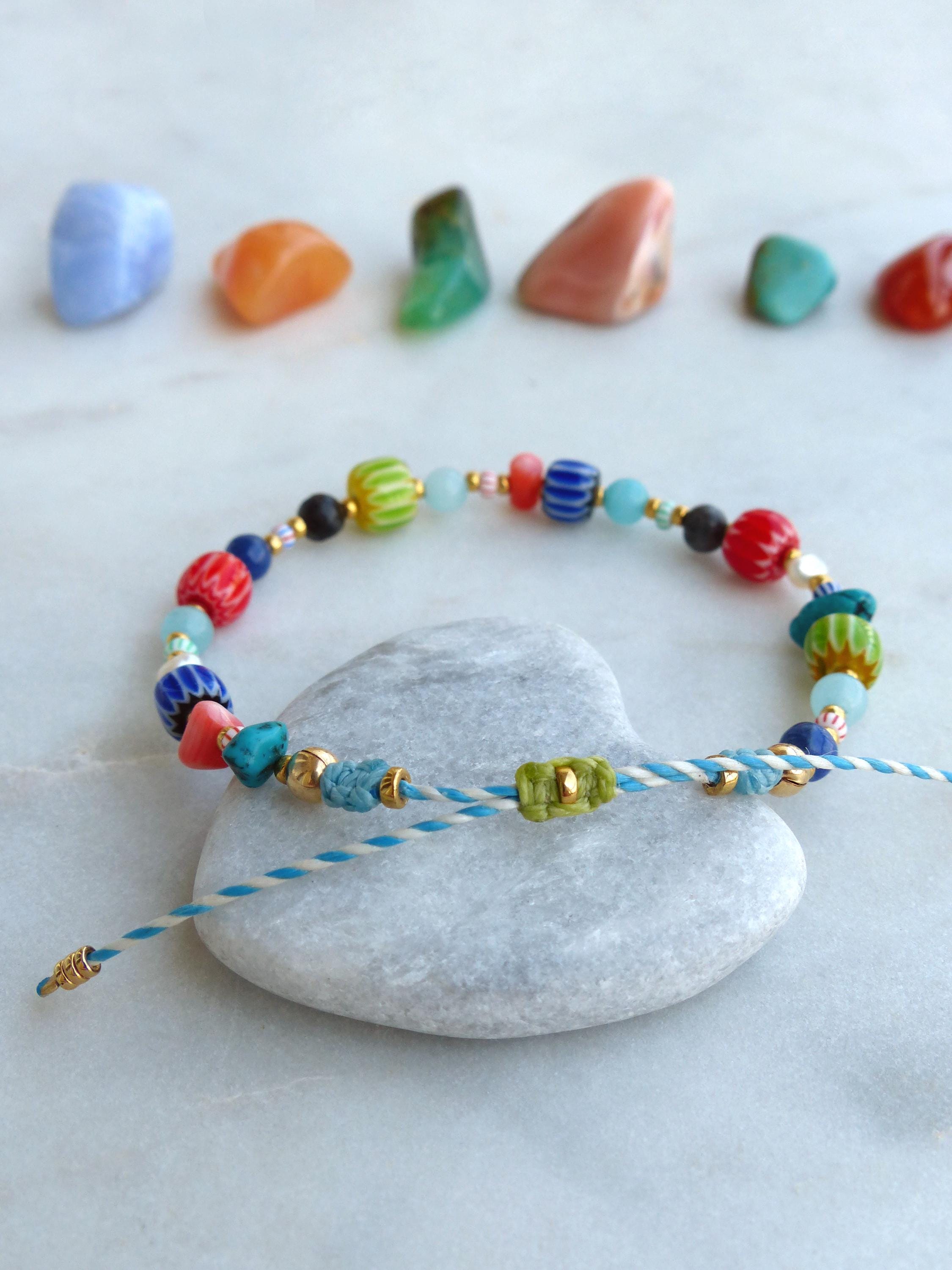 Peut inclure: Un bracelet coloré en perles avec une pierre en forme de cœur et un cordon bleu et blanc. Le bracelet est composé de perles de verre de différentes couleurs, notamment du bleu, du vert, du rouge et de l'orange.