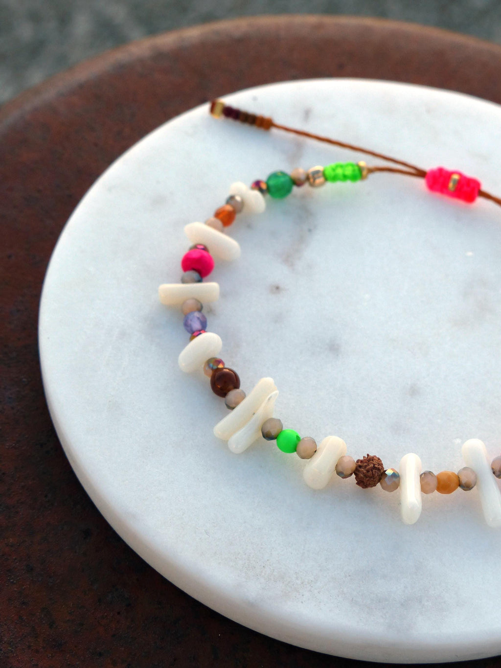Peut inclure: Un bracelet en perles colorées avec des perles blanches, brunes, roses, vertes et violettes. Le bracelet est fait de matériaux naturels et a un design simple et élégant.