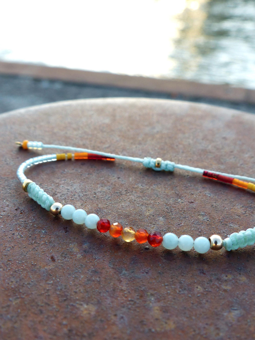 Peut inclure: Un bracelet délicat avec un cordon blanc et de petites perles dans des tons de bleu, orange et rouge. Le bracelet est accentué par des perles dorées.