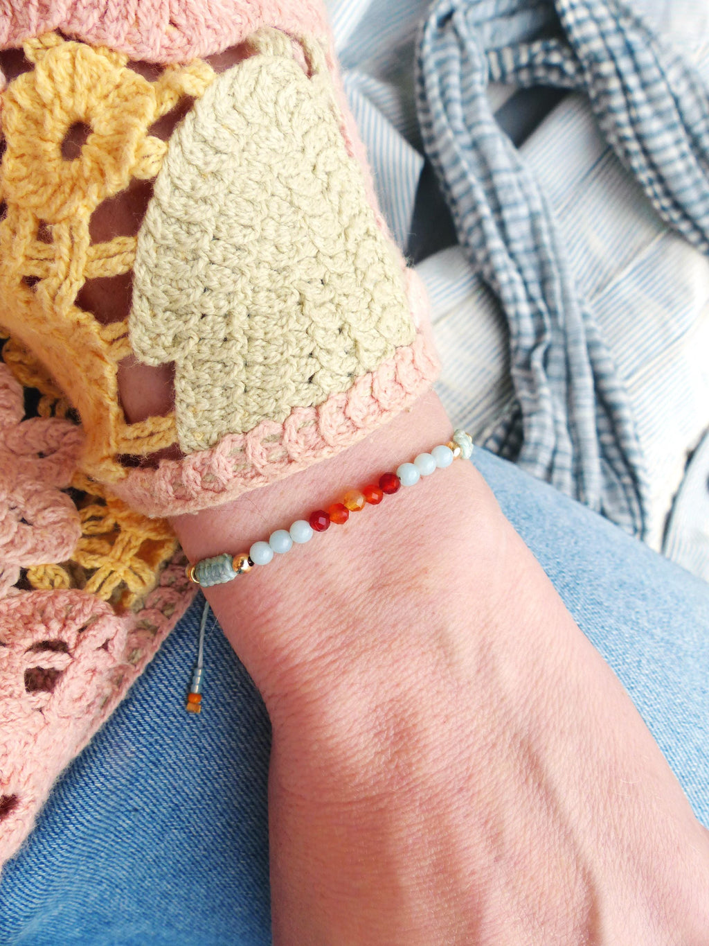 Peut inclure: Un bracelet en perles bleu clair avec un accent doré et de petites perles orange, rouges et jaunes.