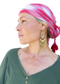 Peut inclure: Une femme portant un foulard à carreaux rouge et blanc avec des glands et une chemise verte à boutons. Elle porte de longues boucles d'oreilles en perles colorées.