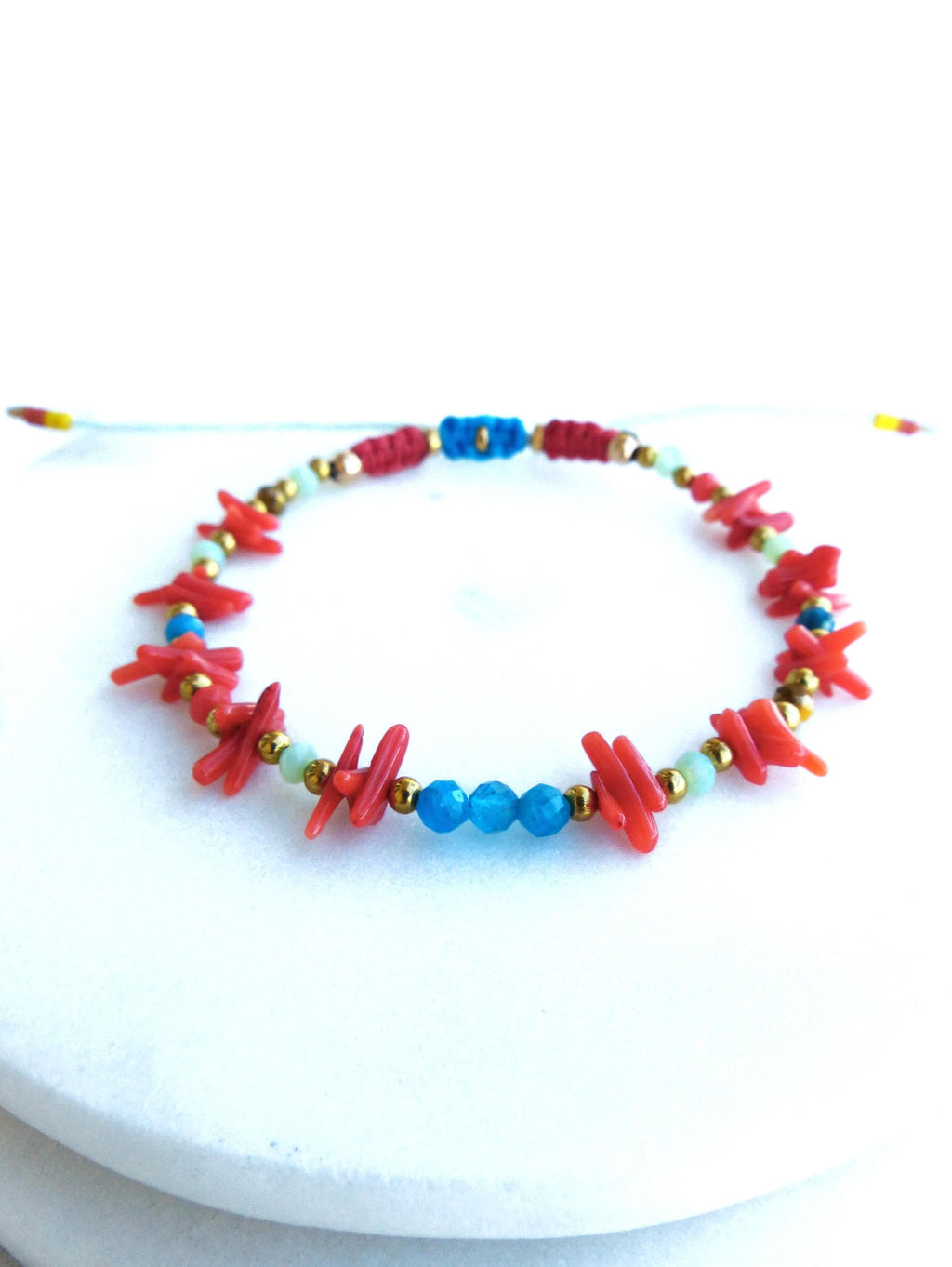 Peut inclure: Un bracelet en corail rouge et pierres bleues avec des perles dorées. Le bracelet est fait de matériaux naturels et a un design simple et élégant.