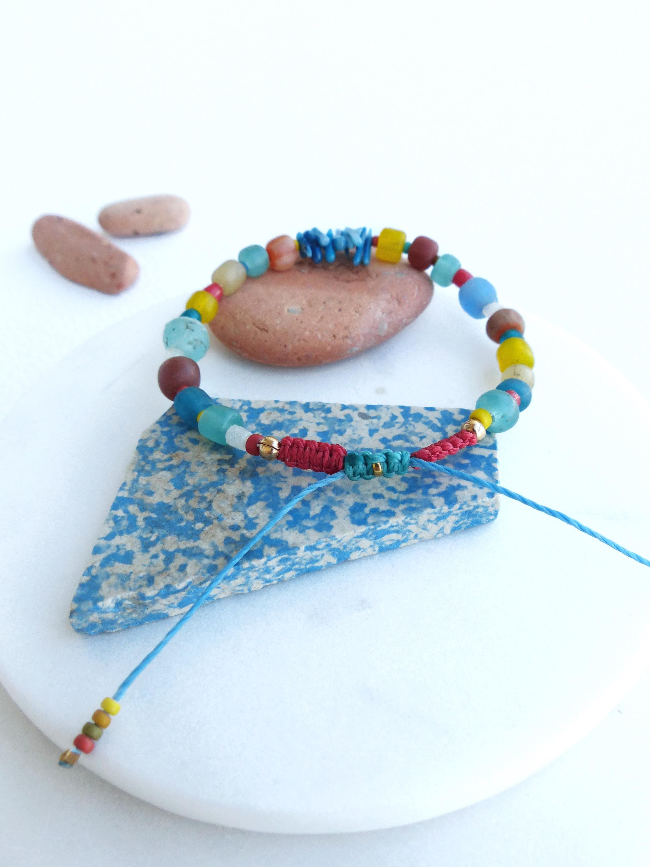 Peut inclure: Un bracelet coloré en perles avec un cordon rouge, bleu et vert. Les perles sont un mélange de bleu, vert, jaune, rouge et marron.
