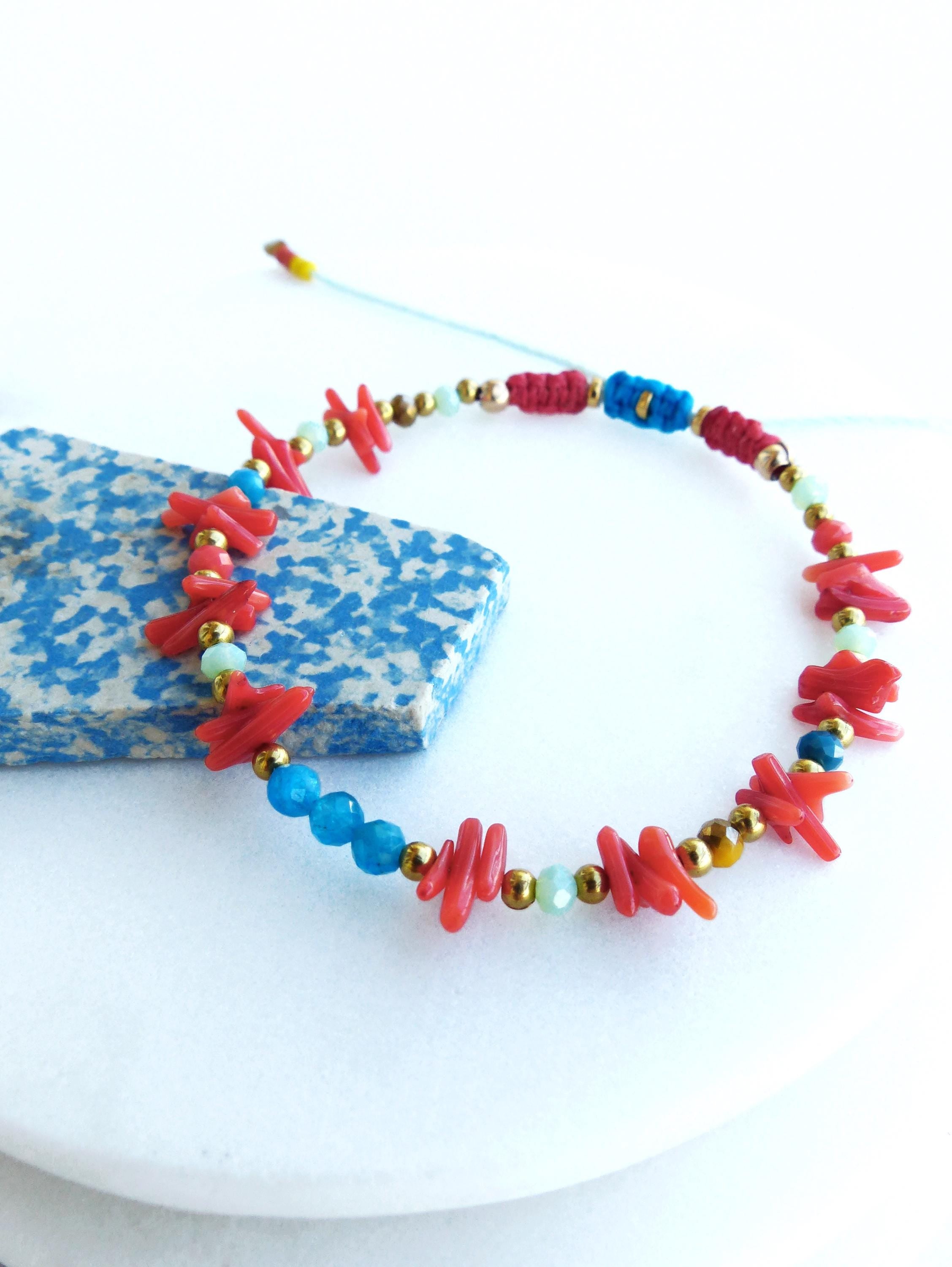 Peut inclure: Un bracelet en perles colorées avec du corail rouge, des pierres bleues et vertes et des accents dorés.