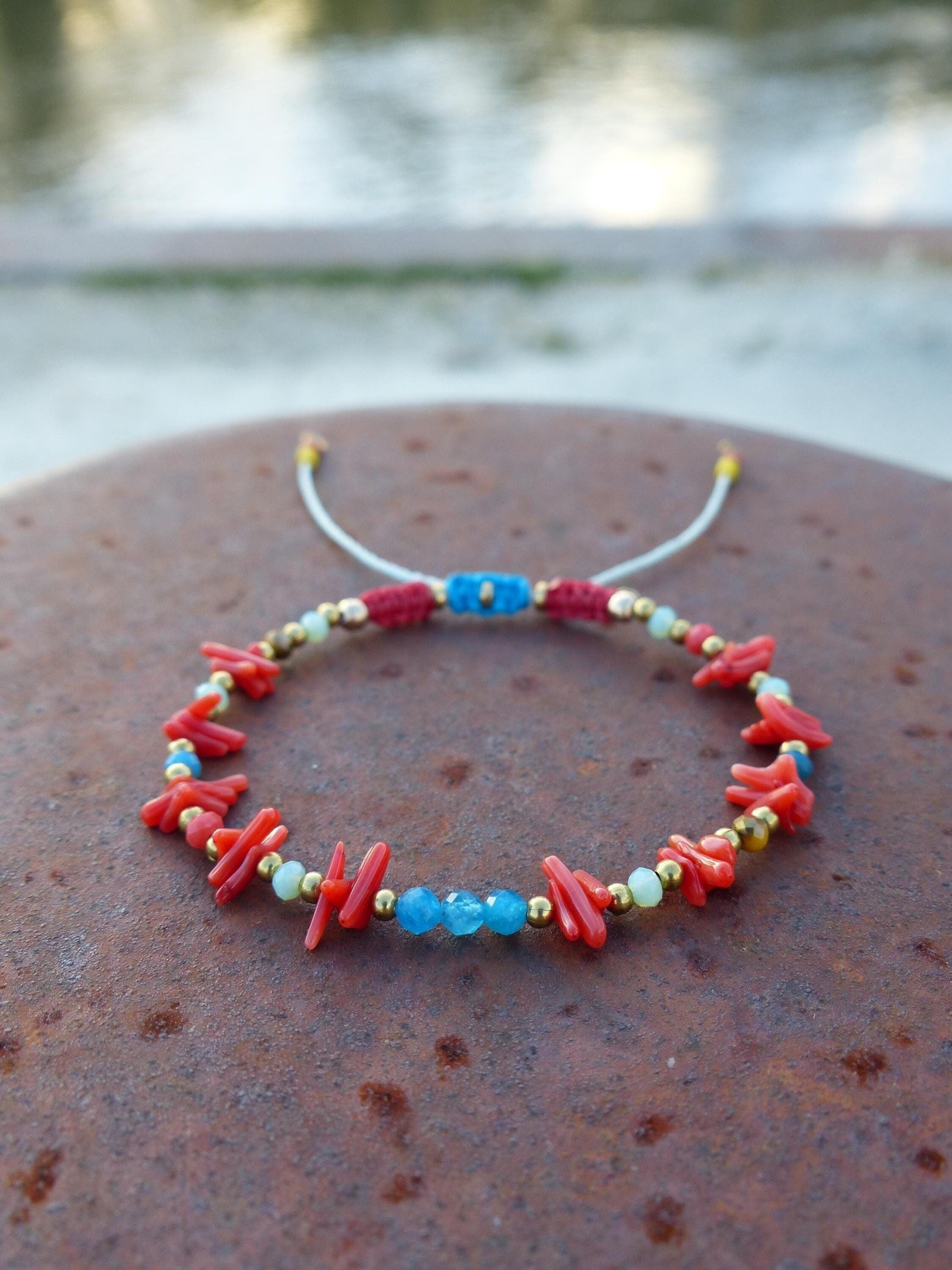 Peut inclure: Un bracelet en corail rouge et pierres bleues avec des perles dorées et un cordon blanc.