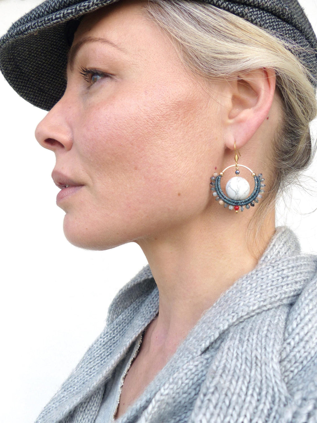 Peut inclure: Boucles d'oreilles dorées avec un centre en pierre blanche et un anneau extérieur perlé dans les tons de bleu, gris et rouge. Les boucles d'oreilles sont suspendues à un crochet doré. Un accessoire unique.