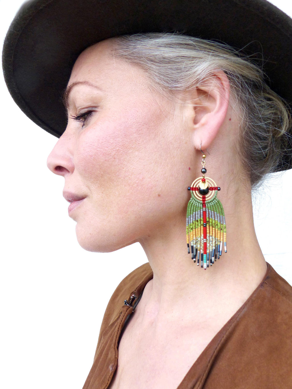 Peut inclure: Une paire de longues boucles d'oreilles en perles avec un motif géométrique. Les boucles d'oreilles sont faites de plusieurs couleurs, dont le vert, le rouge, le jaune et le noir. Les boucles d'oreilles pendent à l'oreille d'une personne.