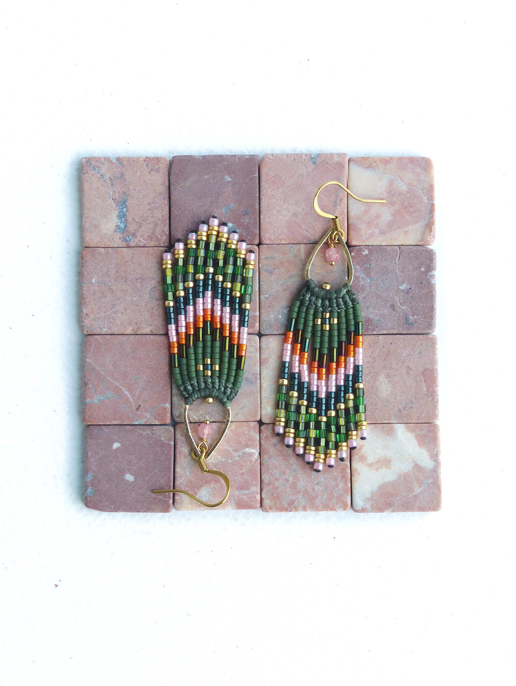 Peut inclure: Une paire de longues boucles d'oreilles en perles vertes, roses et dorées avec un design en forme de larme. Les boucles d'oreilles sont suspendues à des crochets dorés.