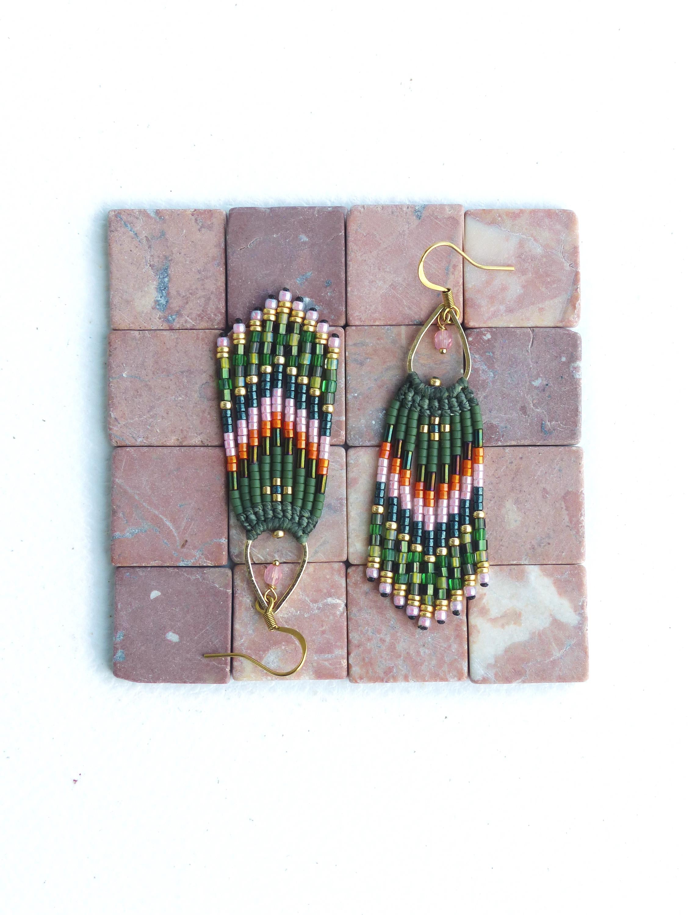 Peut inclure: Une paire de longues boucles d'oreilles en perles vertes, roses et dorées avec un design en forme de larme. Les boucles d'oreilles sont suspendues à des crochets dorés.