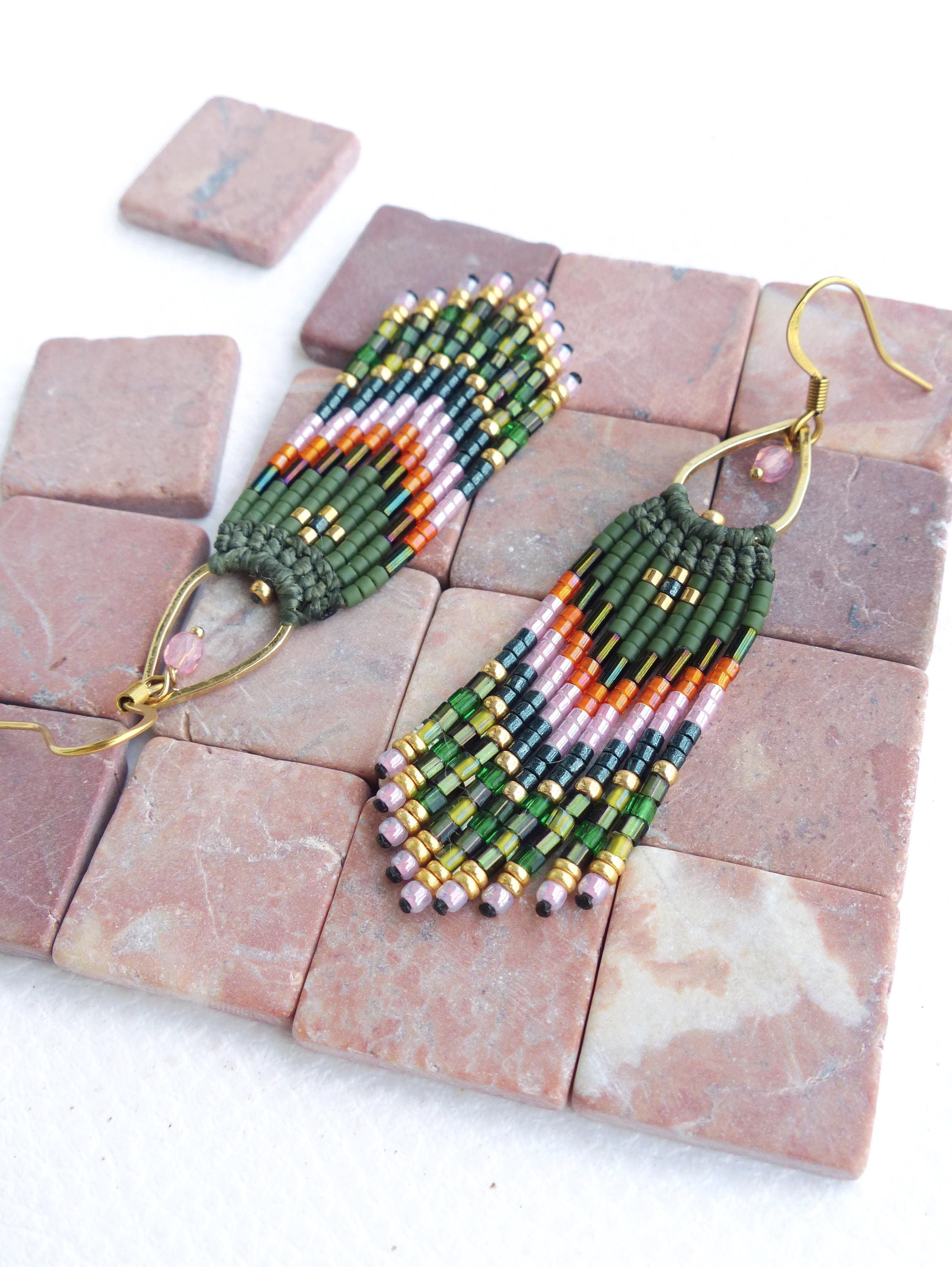 Peut inclure: Une paire de boucles d'oreilles en perles vertes, roses et orange avec des crochets dorés. Les boucles d'oreilles sont faites de petites perles de rocaille et ont un design en forme de frange.