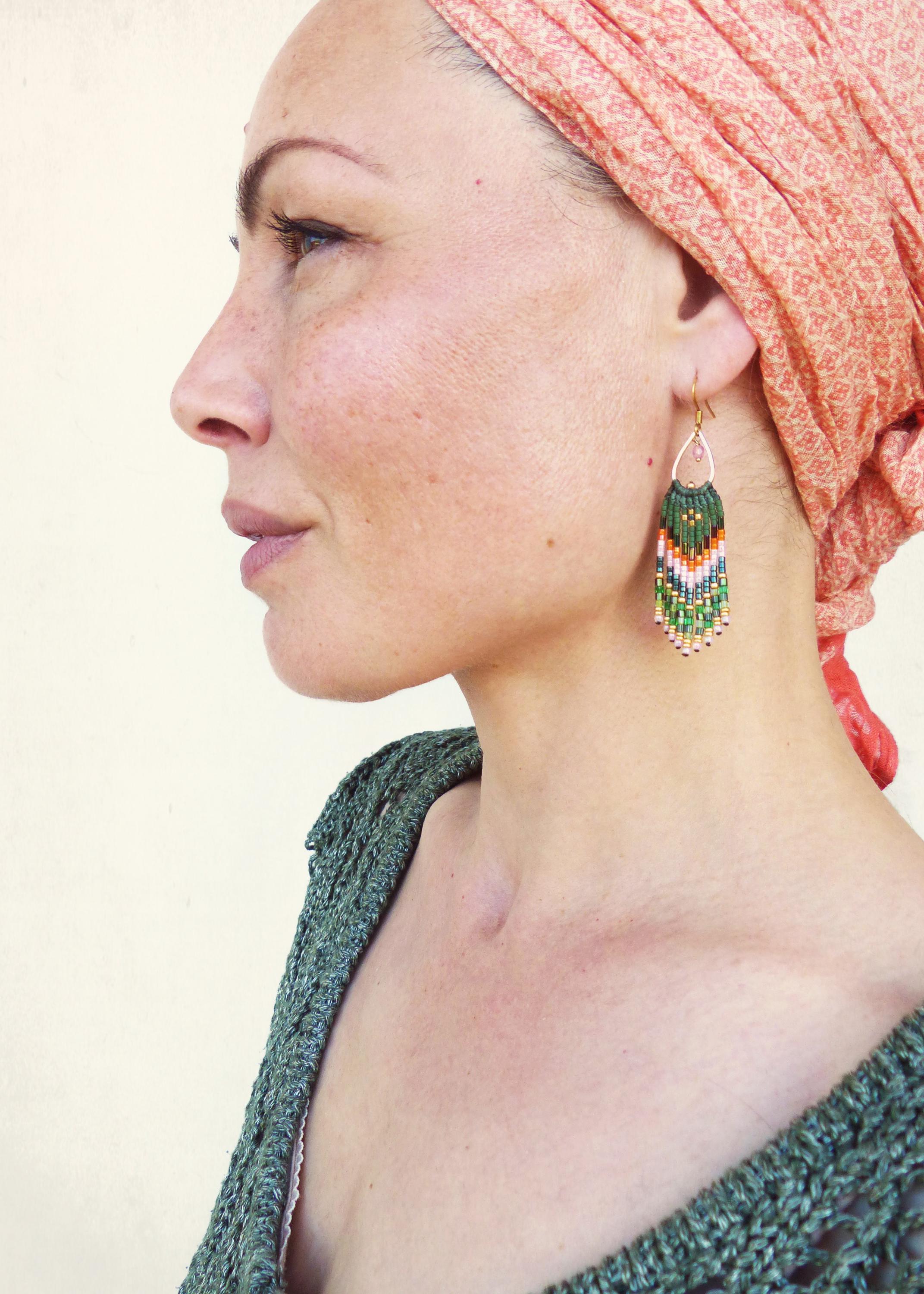 Peut inclure: Une femme portant un foulard de couleur pêche avec une boucle d'oreille à franges en perles vertes, blanches et orange.