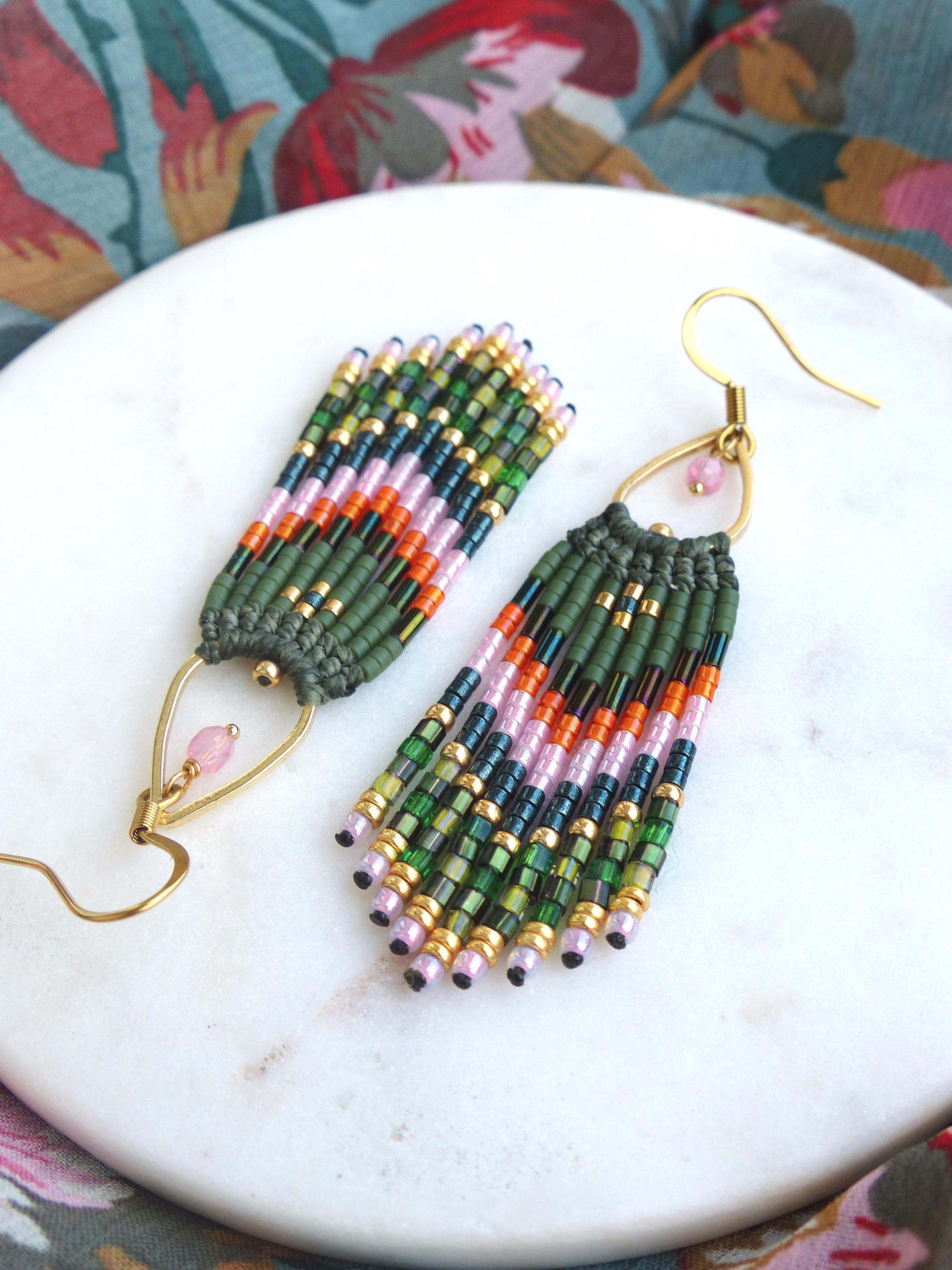 Peut inclure: Une paire de longues boucles d'oreilles en perles avec un crochet doré et une perle rose au sommet. Les perles sont vertes, roses, orange et noires.