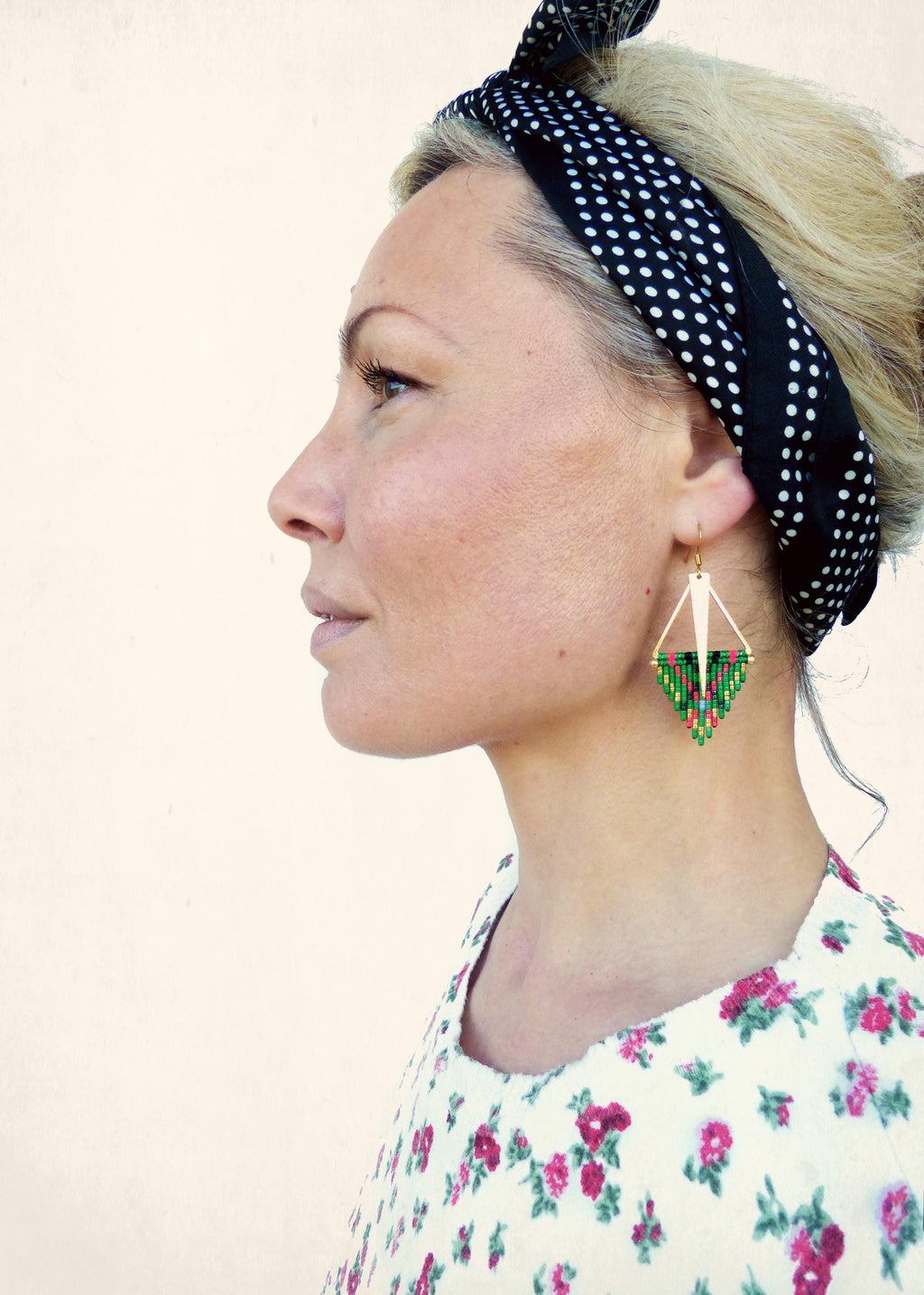 Peut inclure: Une femme portant un bandeau à pois noirs et blancs et une robe à fleurs blanches avec des boucles d'oreilles en perles vertes et rouges.