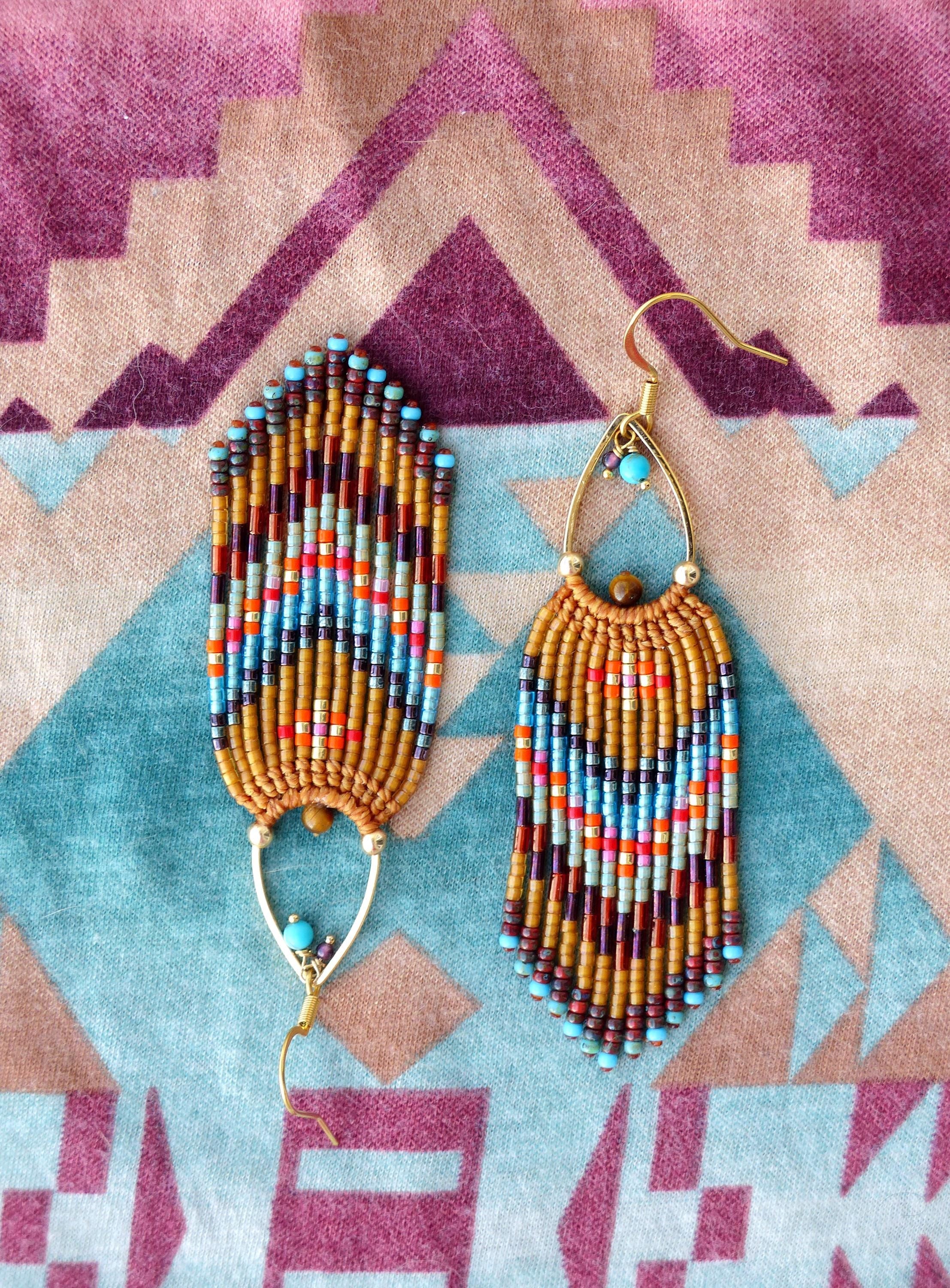 Peut inclure: Paire de boucles d'oreilles faites à la main avec un design bohème. Elles présentent des perles marron, orange, bleues et turquoise disposées verticalement. Les crochets d'oreilles dorés et une perle turquoise ajoutent une touche d'originalité.