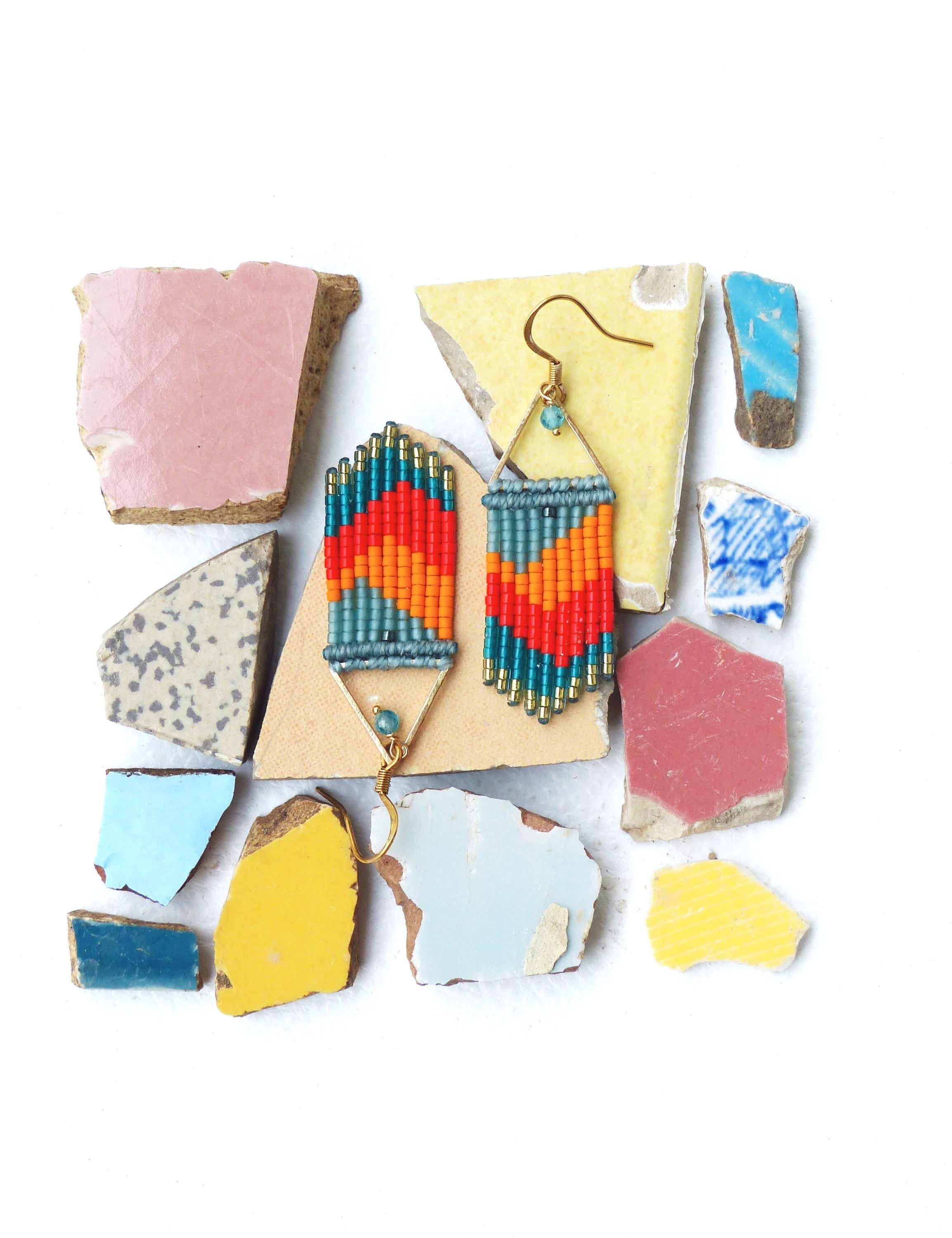 Peut inclure: Une paire de boucles d'oreilles en perles colorées avec un motif géométrique. Les boucles d'oreilles sont faites de perles turquoise, orange et rouges et ont des crochets dorés.