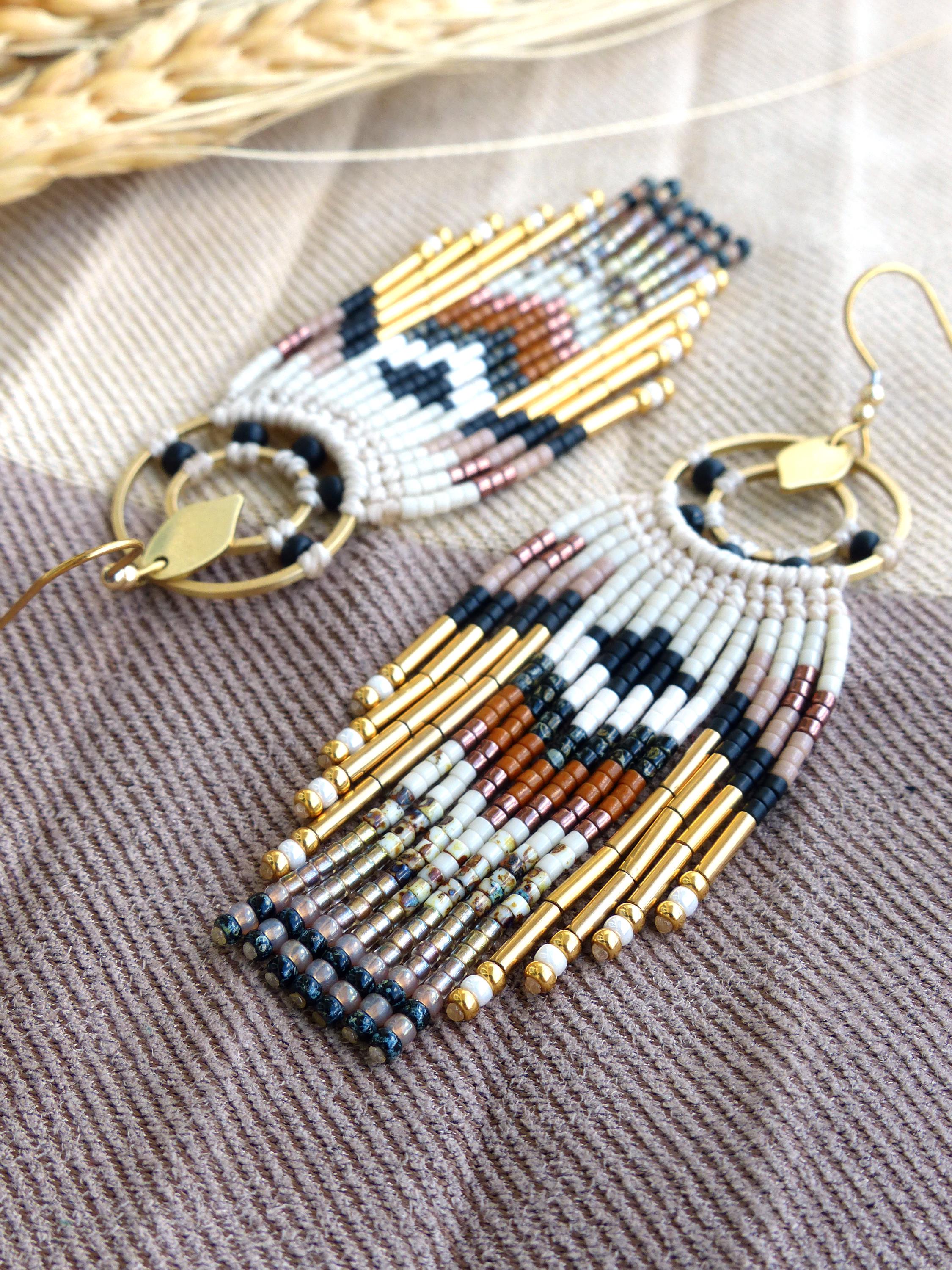 Peut inclure: Une paire de boucles d'oreilles perlées avec un motif géométrique. Les boucles d'oreilles présentent une combinaison de perles blanches, noires, dorées, marron et roses. Elles ont un anneau en métal doré et un petit accent en forme de feuille. 