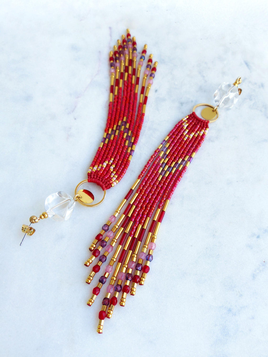 Peut inclure: Paire de boucles d'oreilles faites à la main avec des perles rouges, dorées et violettes. Les boucles d'oreilles présentent de longues franges, des accents dorés et un cristal transparent. Elles sont conçues avec un anneau et une tige dorés.
