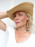 Peut inclure: Un chapeau de paille à larges bords et des boucles d'oreilles en perles. Les boucles d'oreilles sont longues et présentent un motif coloré de perles roses, bleues et turquoise. Le chapeau est de couleur beige clair et semble être fait de paille tressée.