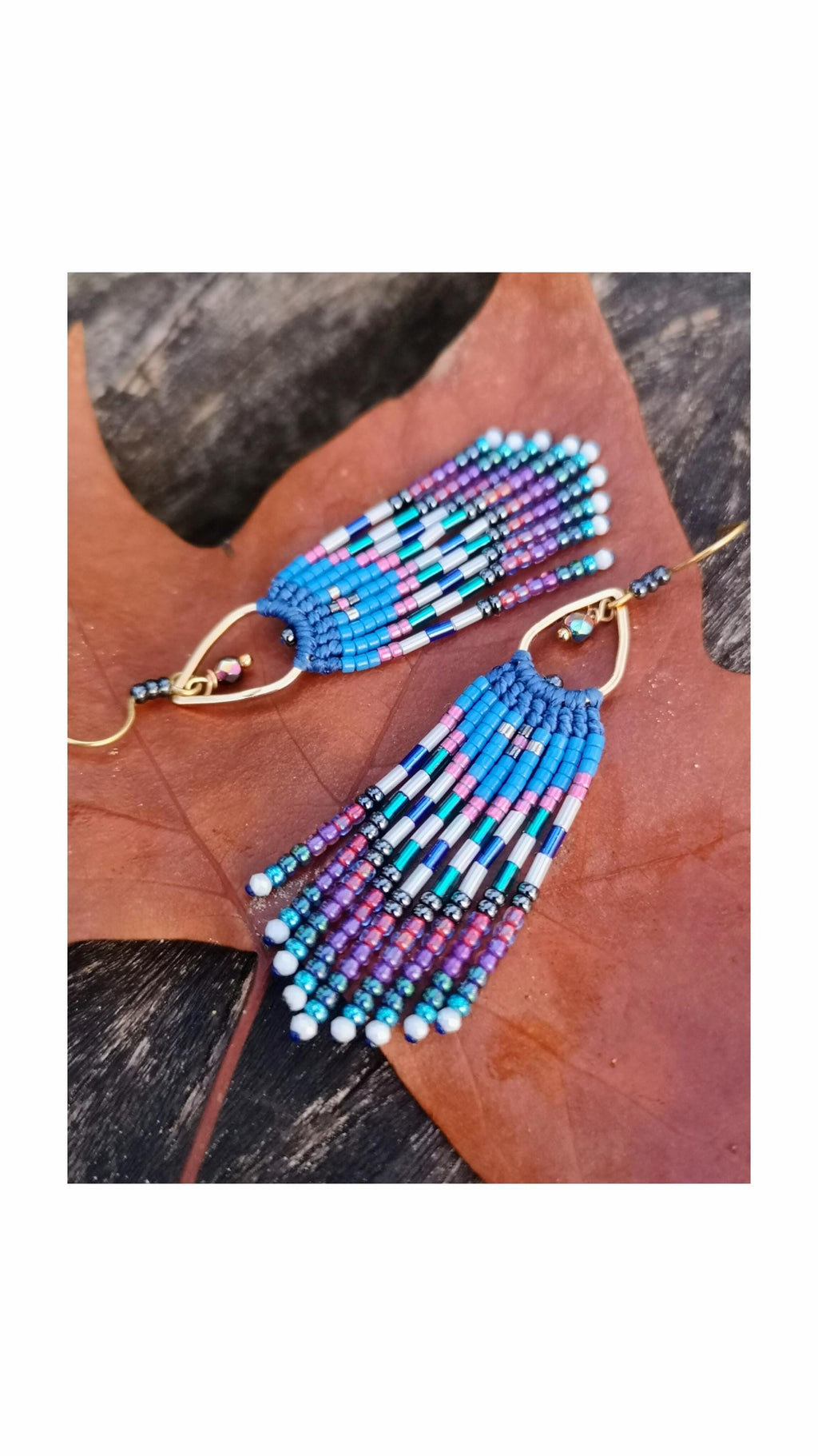 Peut inclure: Une paire de boucles d'oreilles perlées faites à la main avec un design à franges. Les boucles d'oreilles présentent une combinaison de perles bleues, roses, violettes, blanches et argentées. Les boucles d'oreilles sont suspendues à des crochets d'oreilles dorés.