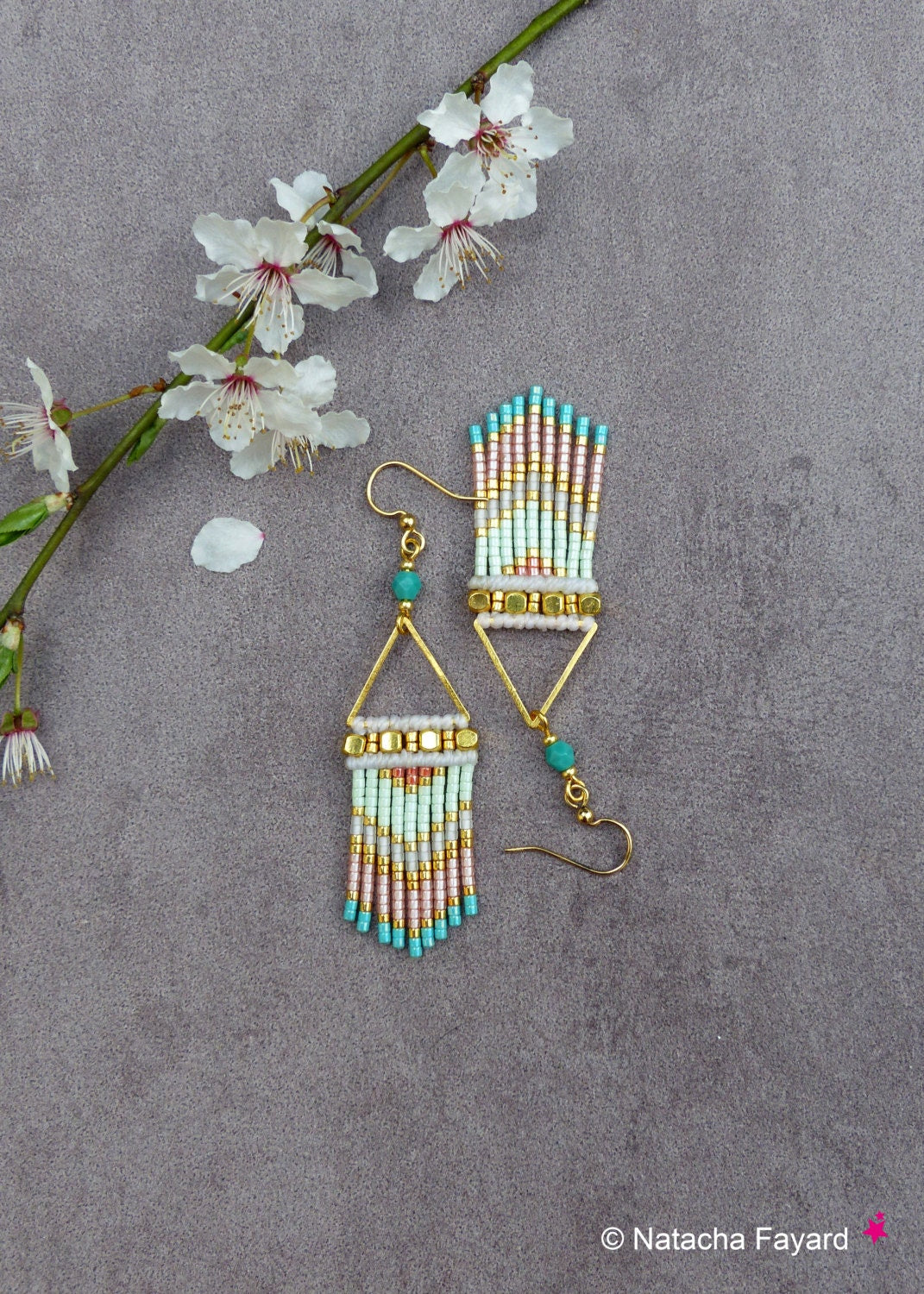 Peut inclure: Une paire de boucles d'oreilles triangulaires dorées avec des perles turquoise et roses. Les boucles d'oreilles ont une frange de perles qui pend de la partie inférieure.