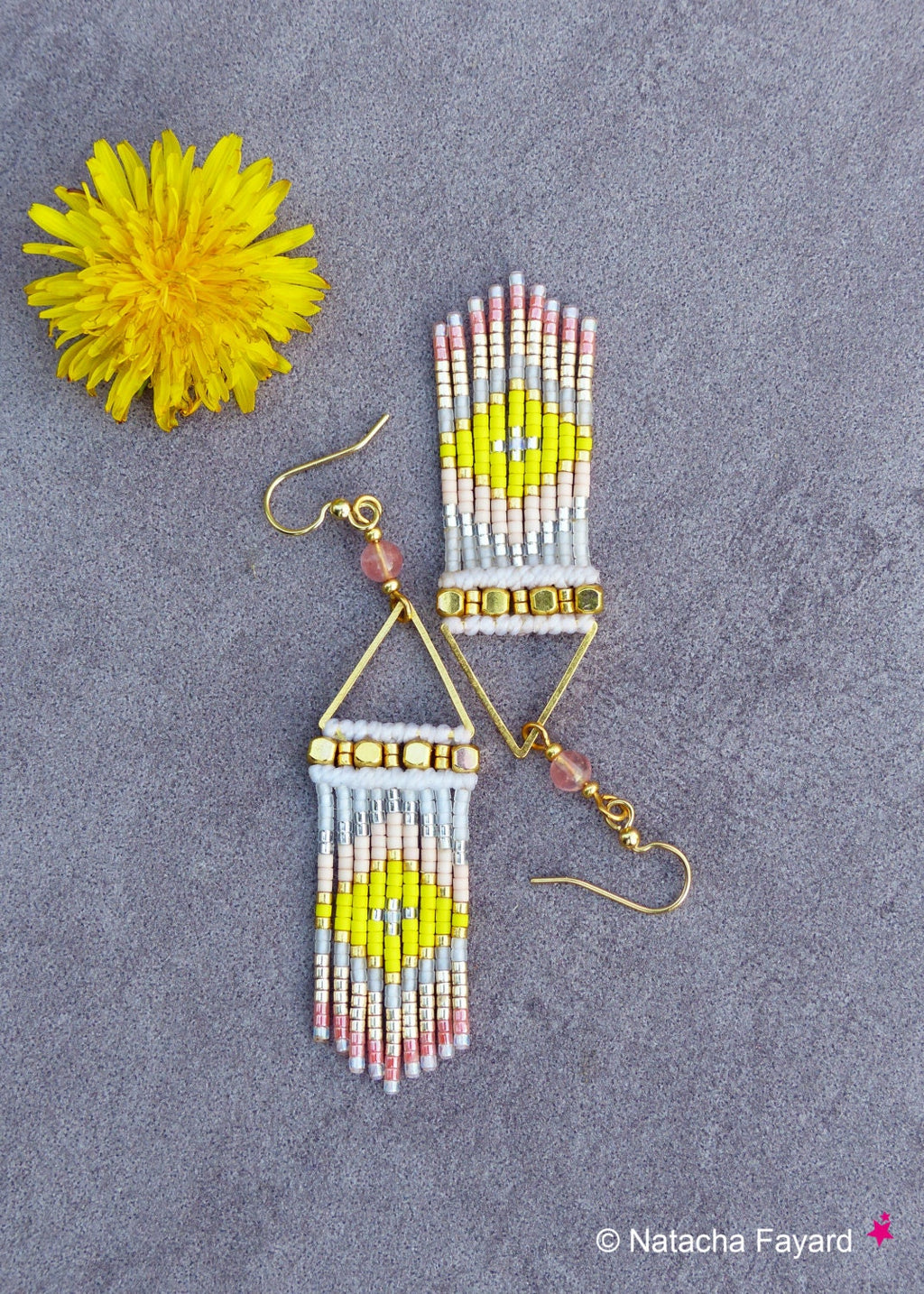 Peut inclure: Une paire de boucles d'oreilles pendantes en forme de triangle doré avec des franges de perles. Les franges sont composées de perles blanches, roses, jaunes et argentées. Les boucles d'oreilles sont suspendues à des crochets dorés.