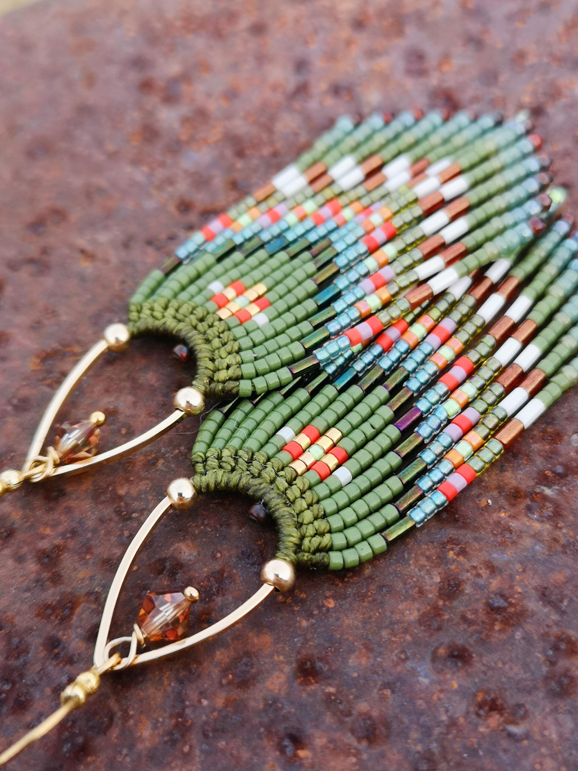 Peut inclure: Boucles d'oreilles faites à la main avec une base verte et des accents colorés de rouge, blanc et bleu. Les boucles d'oreilles comportent un fil doré et une petite perle facettée marron. Les boucles d'oreilles sont de style frange.