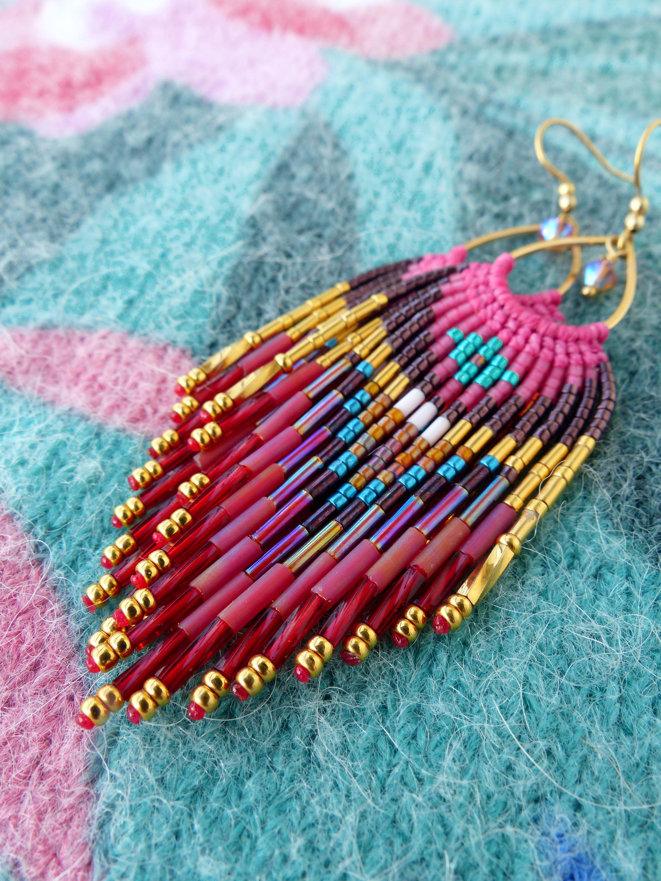 Peut inclure: Boucles d'oreilles perlées faites à la main avec un design à franges. Les boucles d'oreilles présentent une combinaison de perles rouges, dorées, violettes, turquoise et blanches. Les boucles d'oreilles ont des crochets d'oreilles dorés.