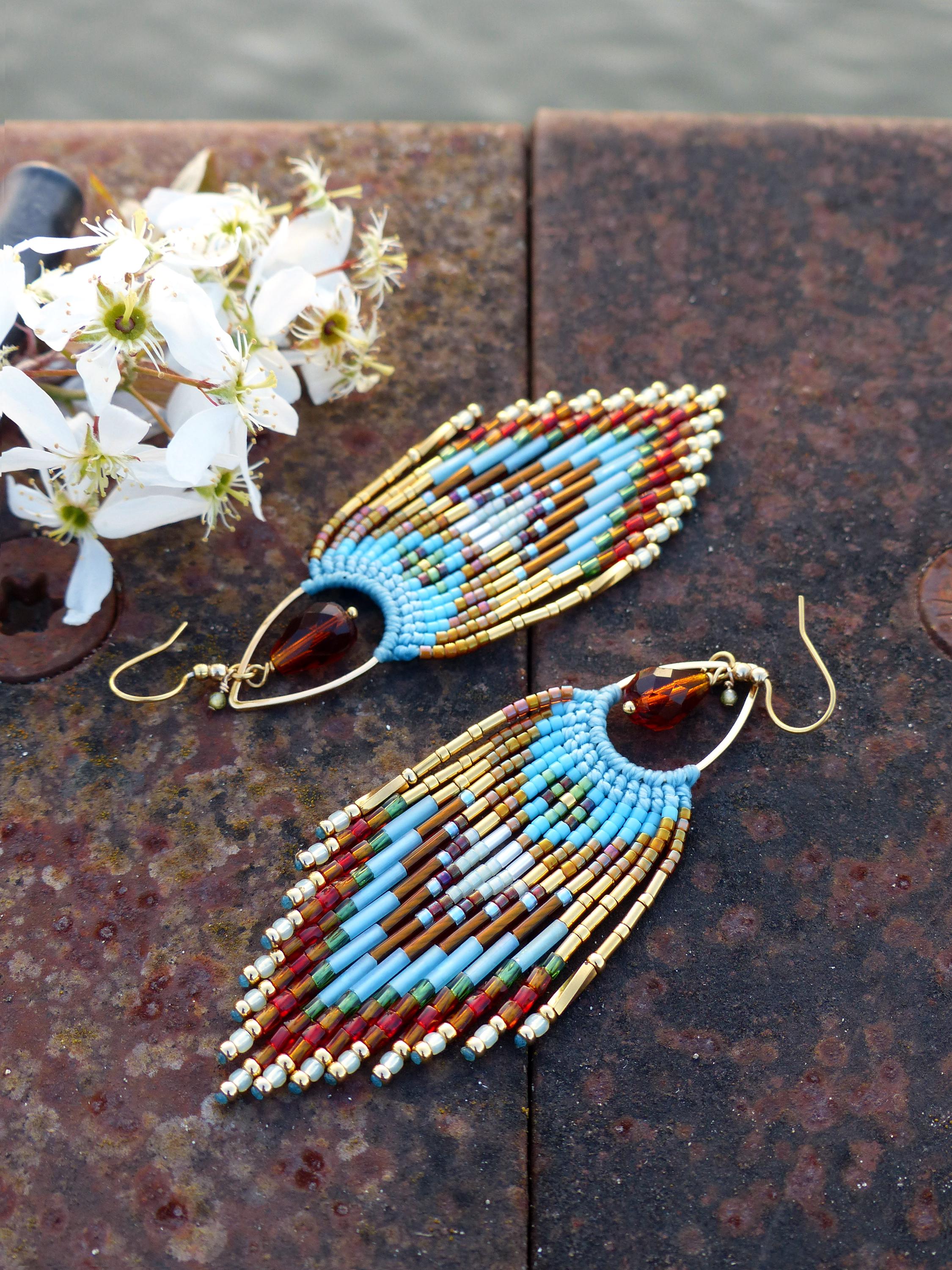 Peut inclure: Boucles d'oreilles faites à la main en perles, en forme de goutte d'eau. Les boucles d'oreilles présentent des perles bleues, dorées, rouges et marron, avec un crochet doré. Les boucles d'oreilles mesurent environ 7.6 cm de long.